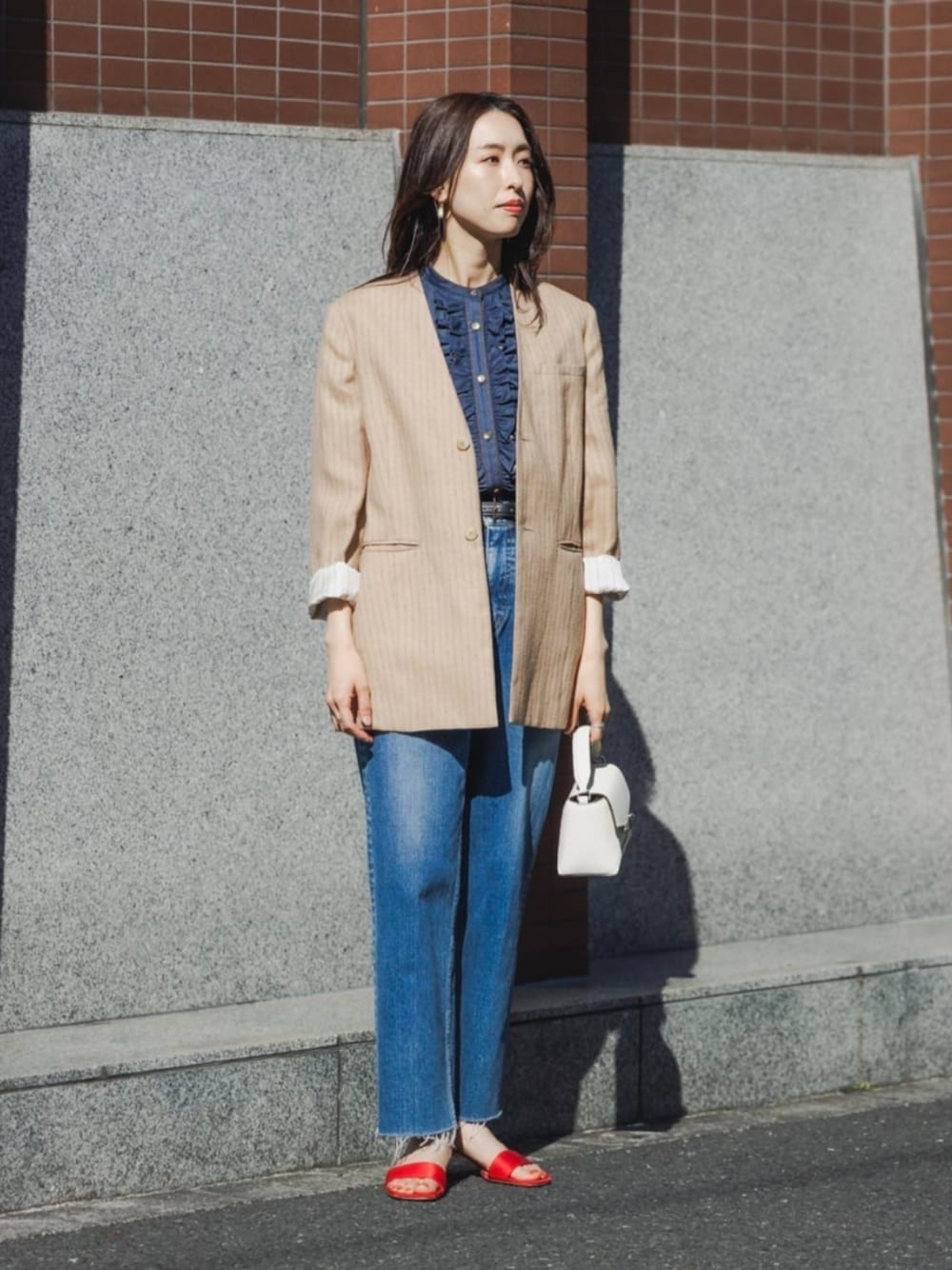 ベージュ系のノーカラージャケット、ブルー系のシャツ/ブラウス、ブルー系のデニムパンツを着用したレディースの春コーディネートの1枚目の写真