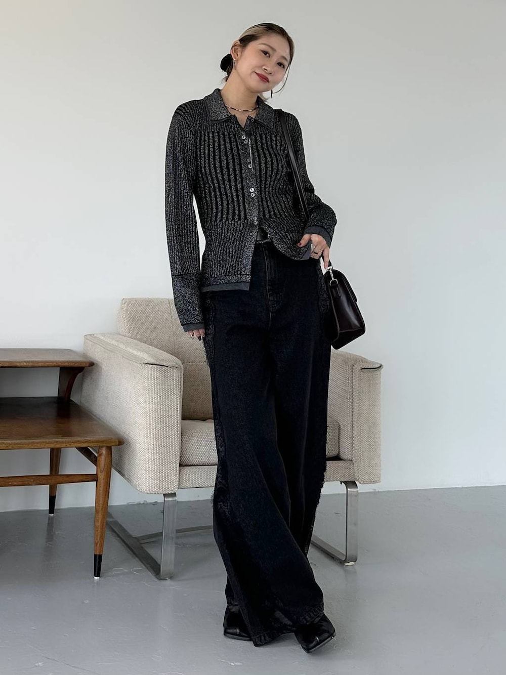 ブラック系のショルダーバッグ、ブラック系のデニムパンツ、ブラック系のブーツを着用したレディースの秋コーディネートの1枚目の写真