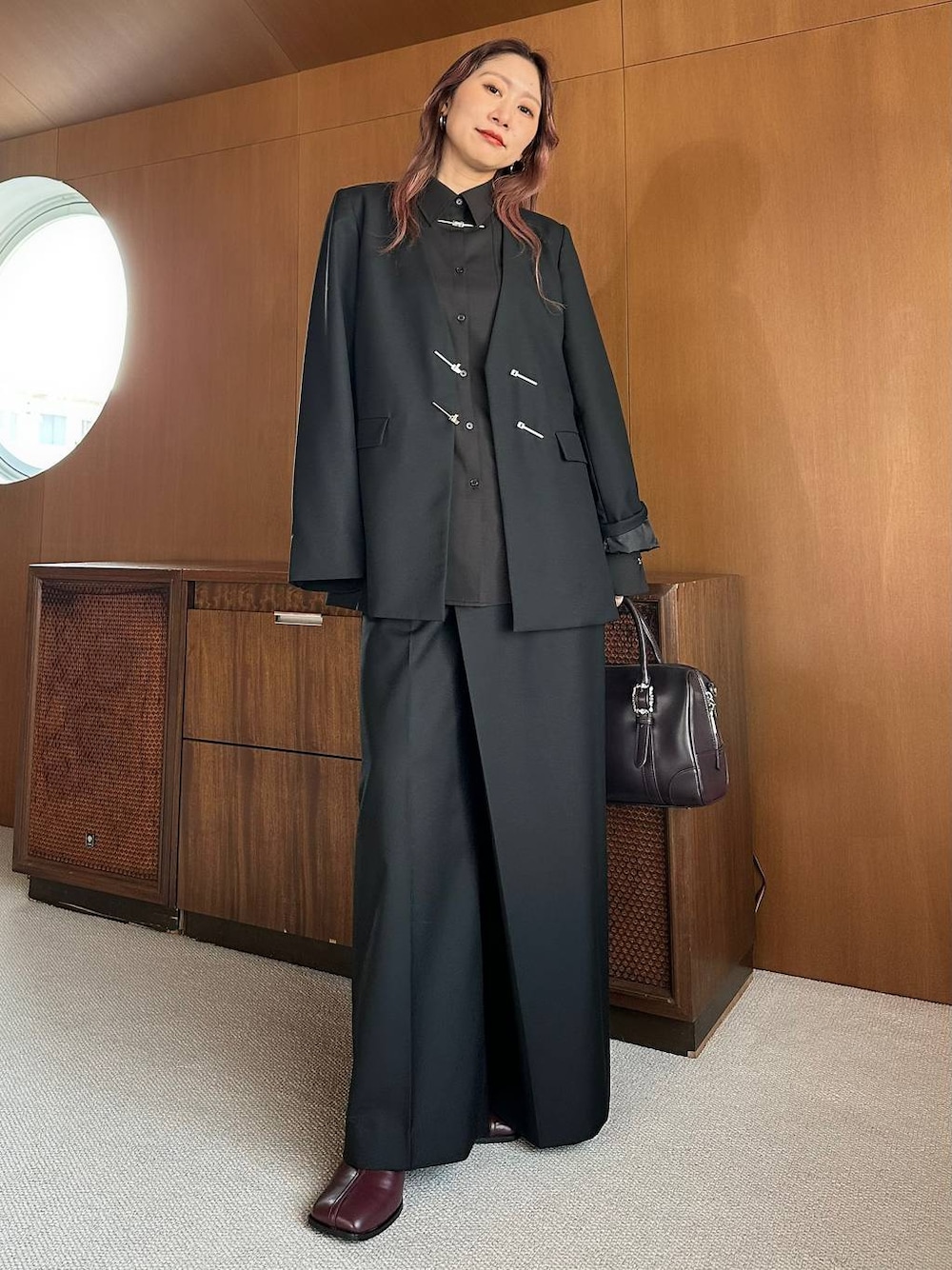 ブラウン系のボストンバッグ、レッド系のブーツを着用したレディースの秋コーディネートの1枚目の写真