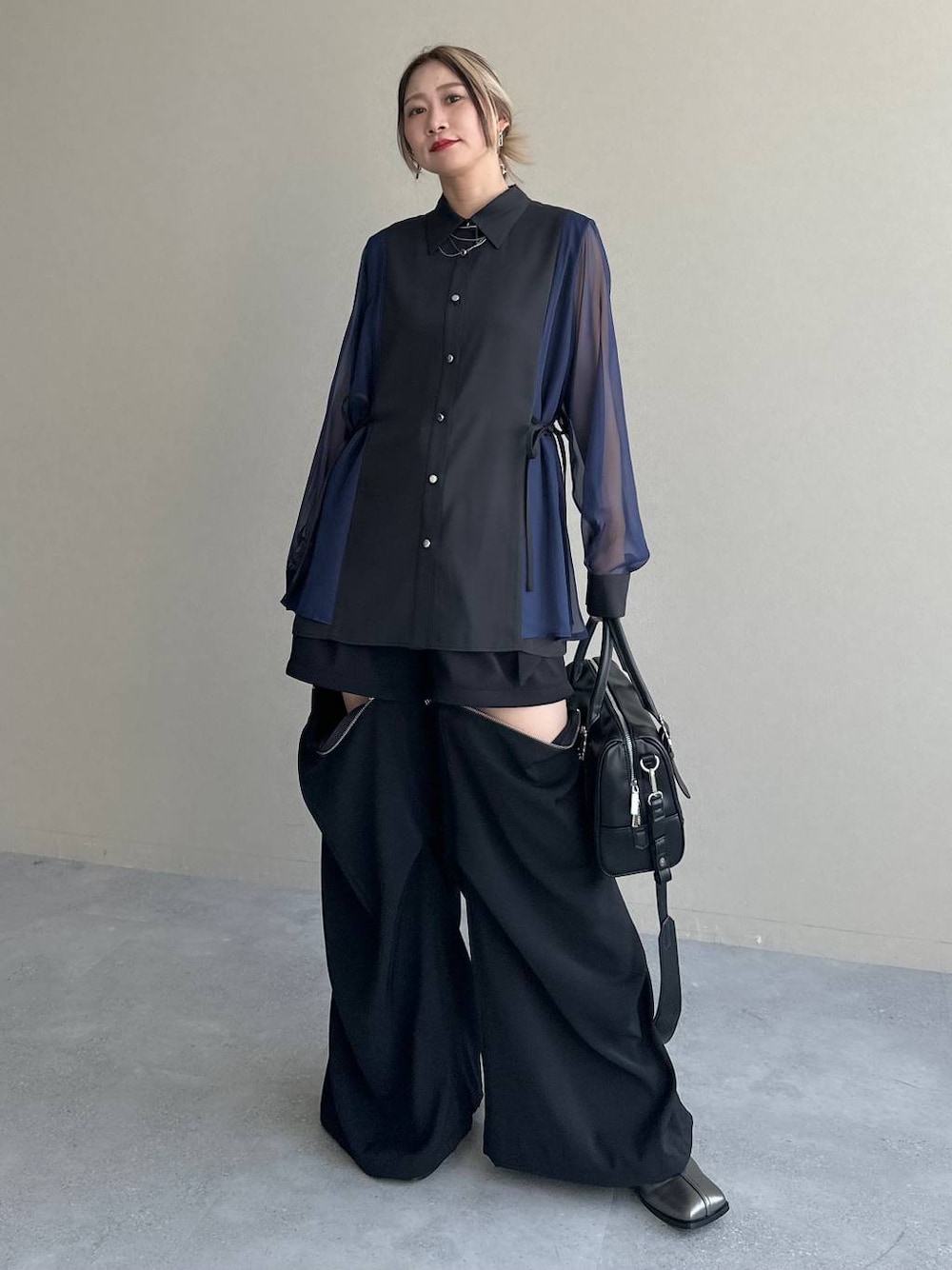 ブラック系のカーゴパンツ、ブラック系のボストンバッグ、シルバー系のブーツを着用したレディースの夏コーディネートの1枚目の写真