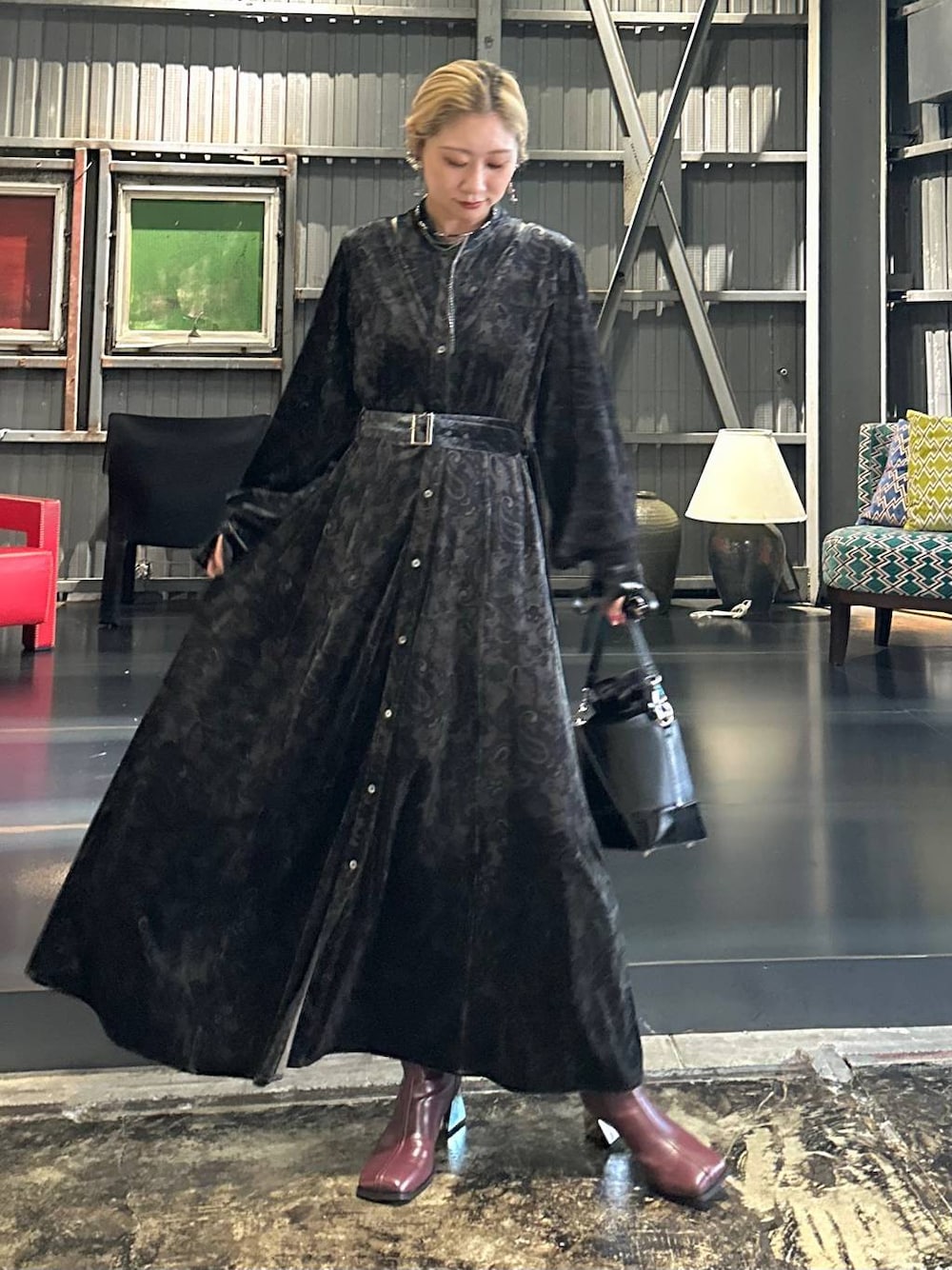 ブラック系のワンピース、レッド系のブーツ、ブラック系のショルダーバッグを着用したレディースの秋コーディネートの1枚目の写真