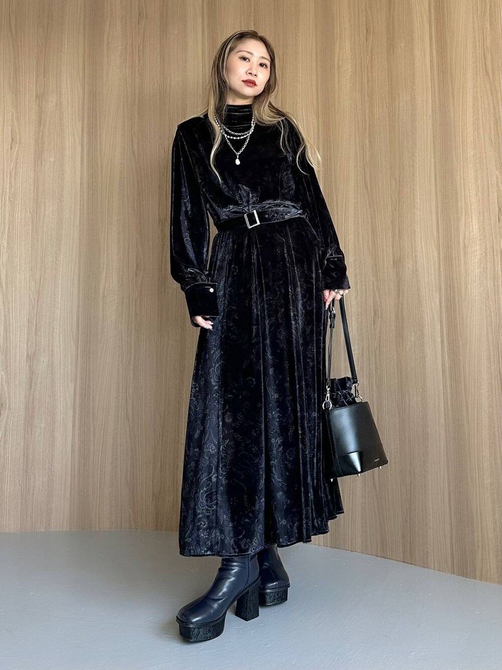 グレー系のワンピース、ブルー系のブーツ、ブラック系のショルダーバッグを着用したレディースの秋コーディネートの1枚目の写真