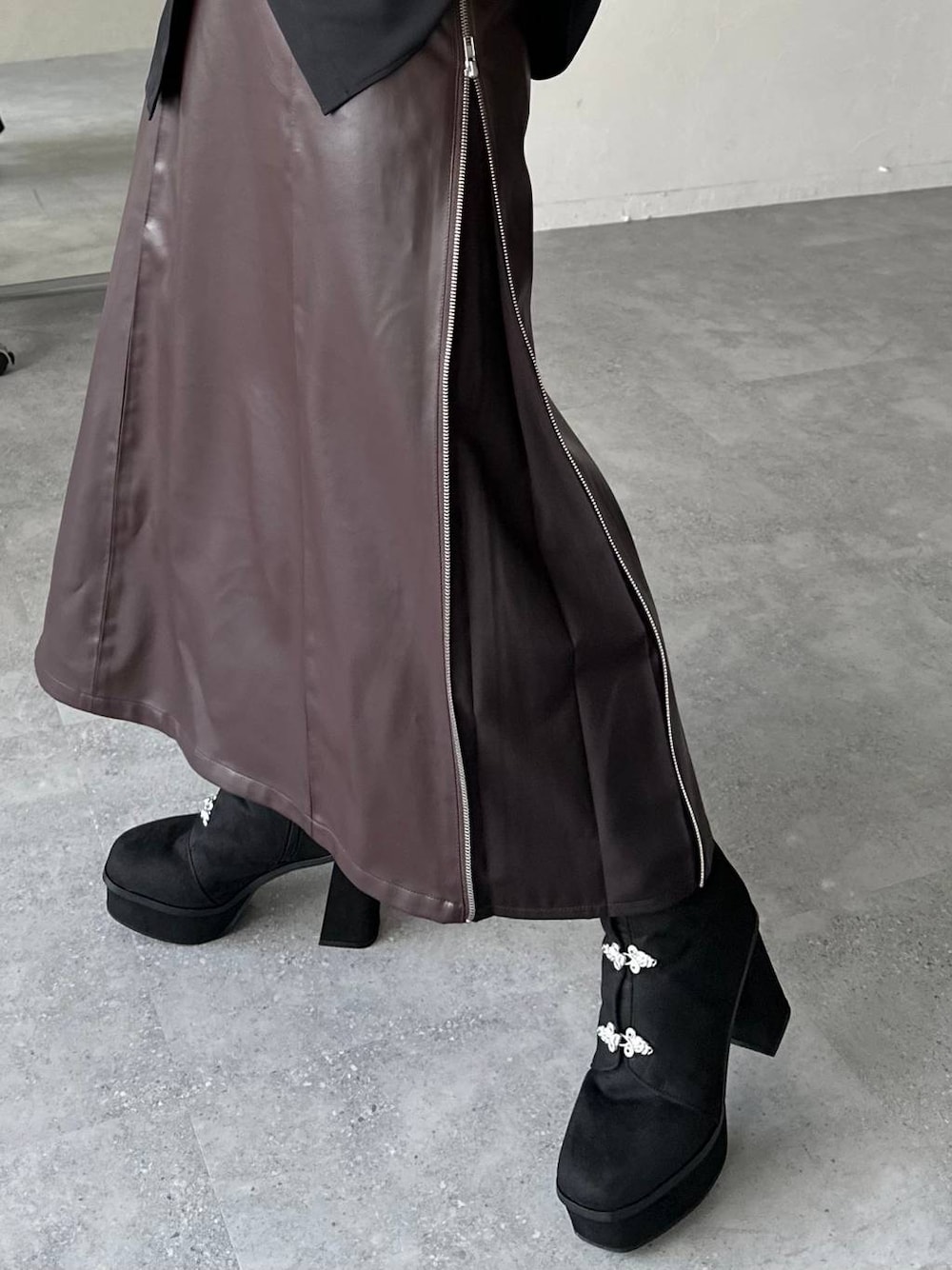 ブラウン系のスカート、ブラック系のブーツを着用したレディースの秋コーディネートの1枚目の写真