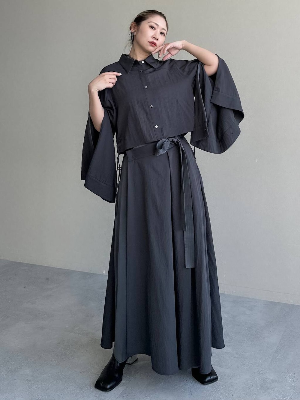 ブラック系のブーツ、グレー系のスカート、グレー系のシャツ/ブラウスを着用したレディースの秋コーディネートの1枚目の写真