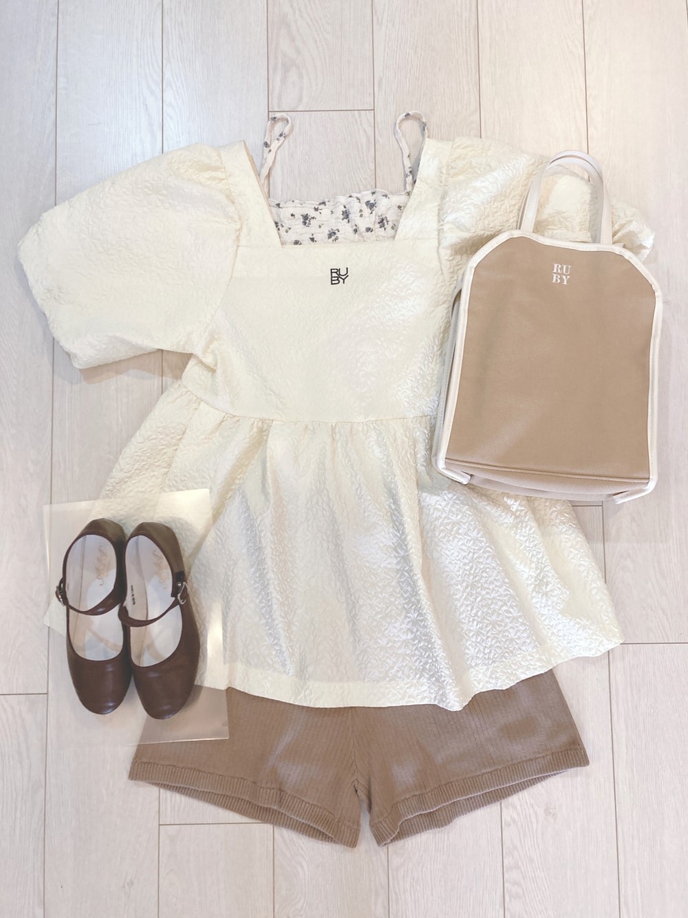 ベージュ系のショルダーバッグ、ホワイト系のトップス、ブラウン系のパンプスを着用したレディースの秋コーディネートの1枚目の写真