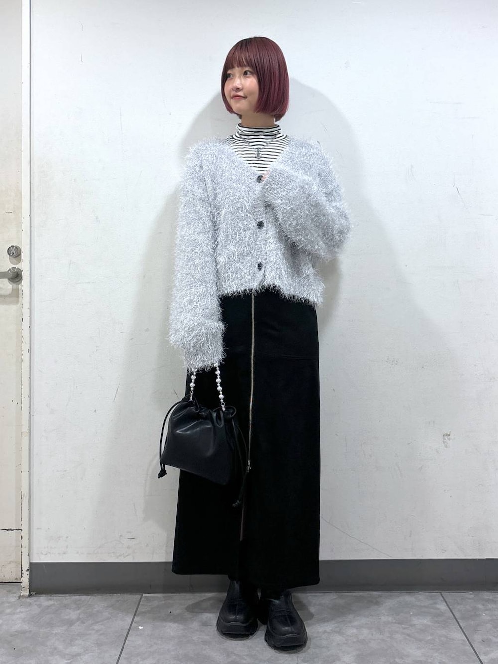 ブラック系のブーツ、ブラック系のスカート、ブラック系のショルダーバッグを着用したレディースの冬コーディネートの1枚目の写真