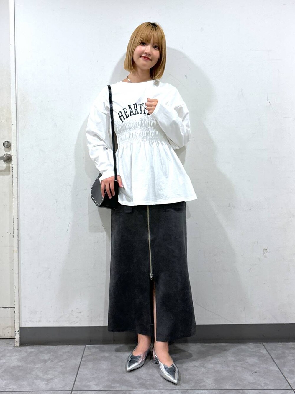 シルバー系のパンプス、ブラック系のショルダーバッグ、グレー系のスカートを着用したレディースの秋コーディネートの1枚目の写真