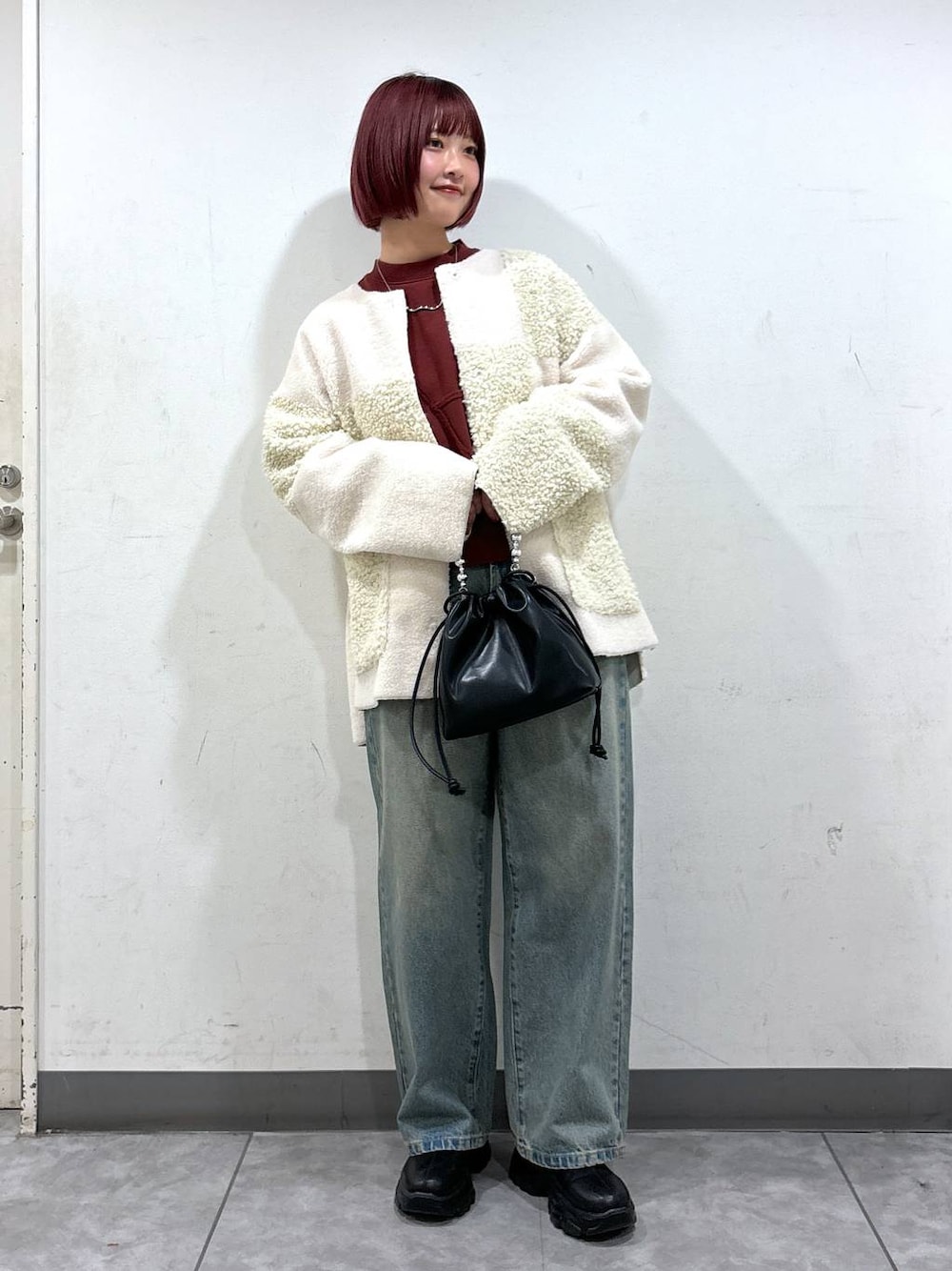 ブルー系のデニムパンツ、ブラック系のブーツ、ブラック系のショルダーバッグを着用したレディースの秋コーディネートの1枚目の写真