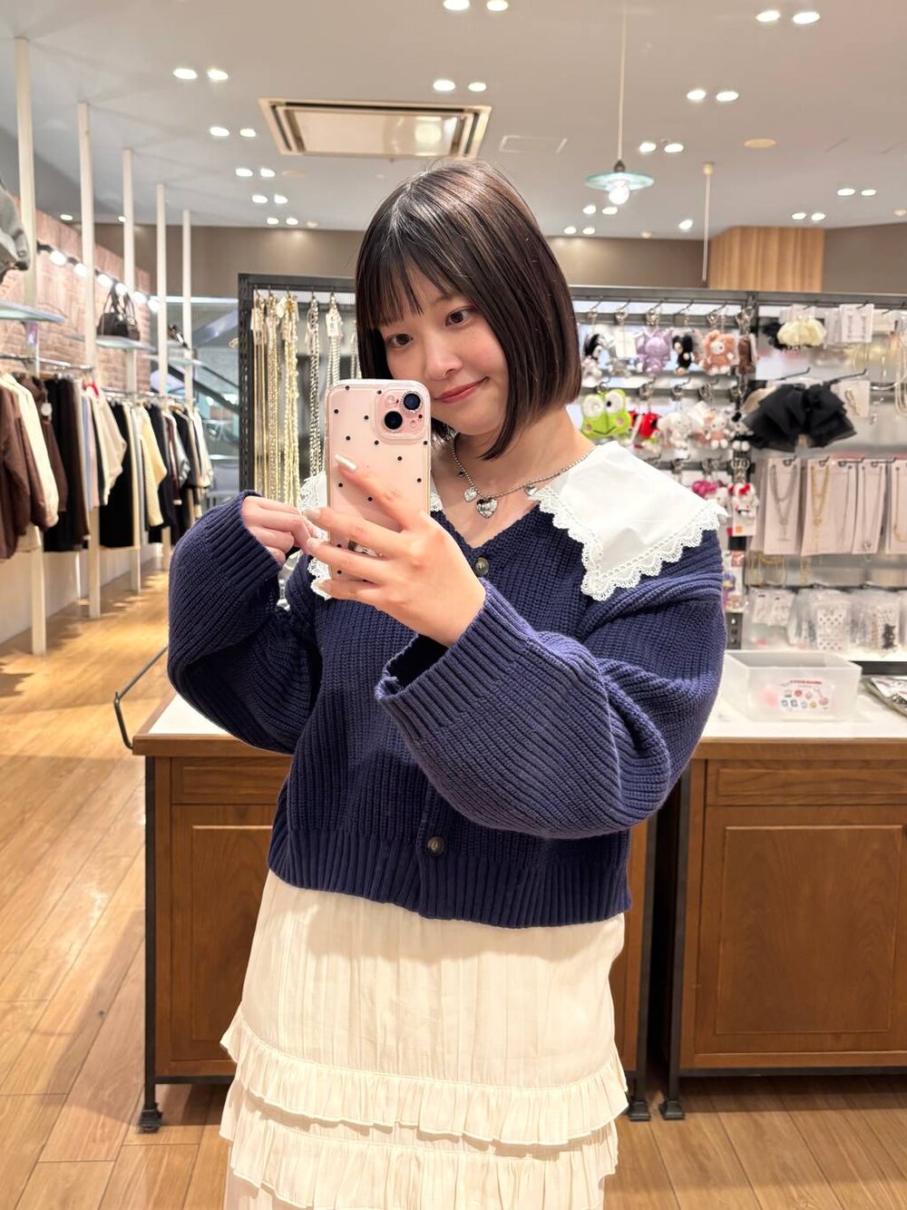 ブラック系のローファー、ホワイト系のスカート、ブルー系のカーディガン/ボレロを着用したレディースの冬コーディネートの1枚目の写真