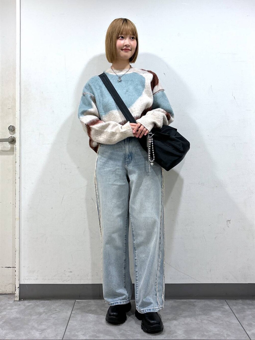 ブルー系のデニムパンツ、ブラック系のブーツ、ブラック系のショルダーバッグを着用したレディースの秋コーディネートの1枚目の写真