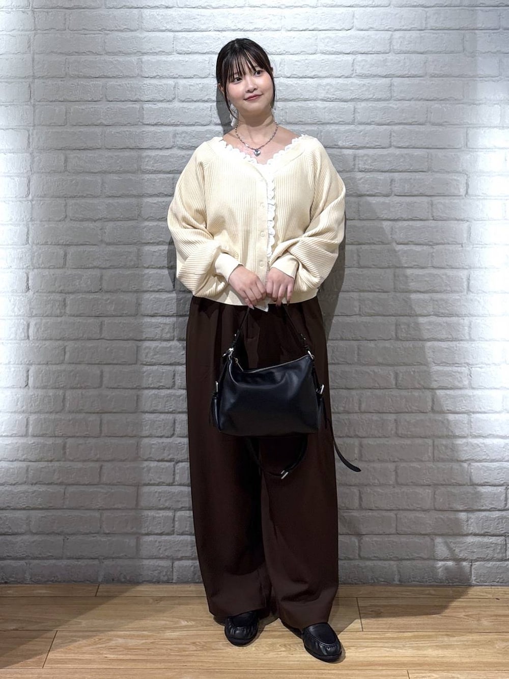 ブラック系のハンドバッグ、ホワイト系のニット/セーター、ブラック系のローファーを着用したレディースの秋コーディネートの1枚目の写真