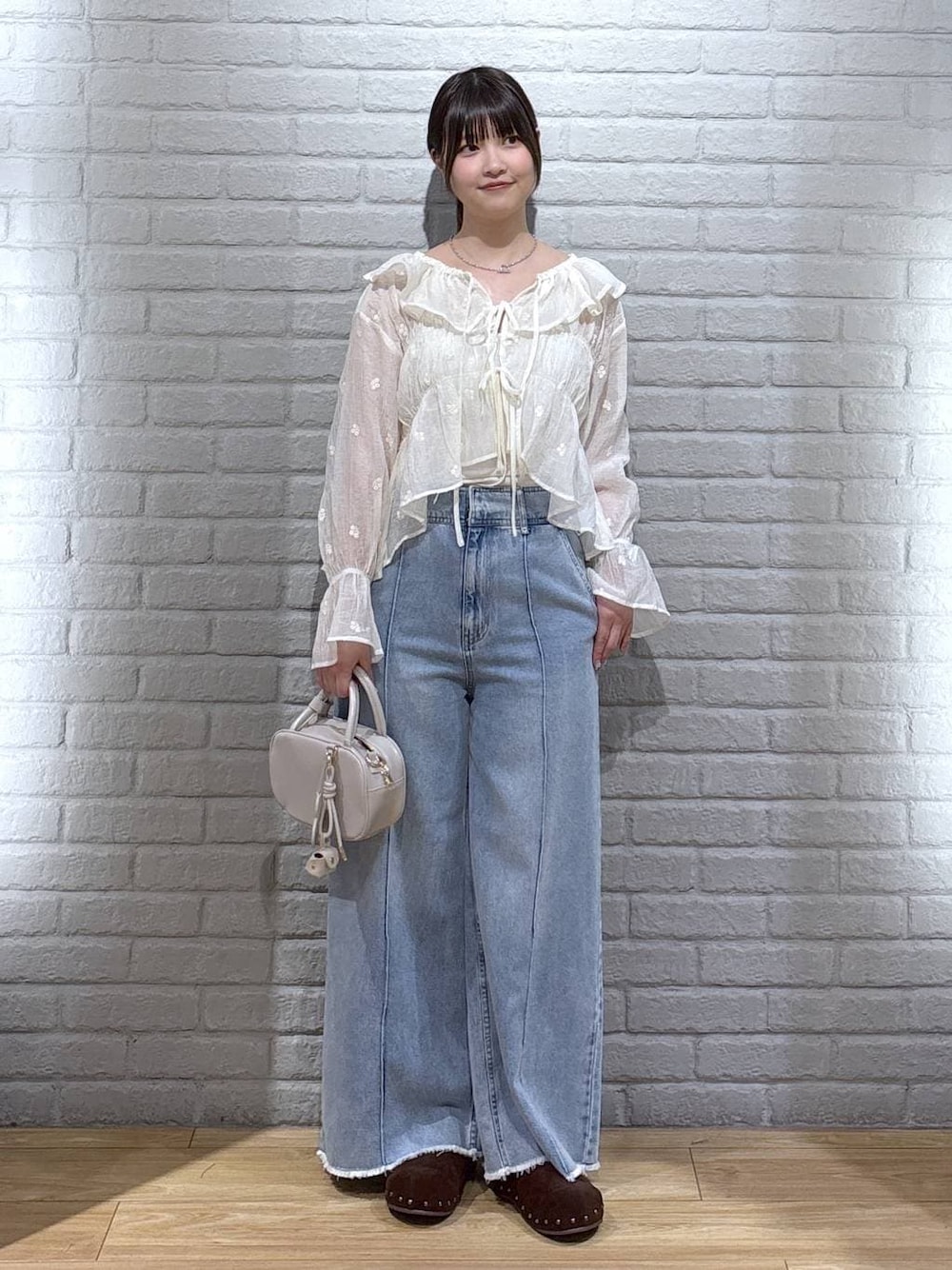 ホワイト系のボストンバッグ、ブルー系のデニムパンツ、ブラウン系のサンダルを着用したレディースの春コーディネートの1枚目の写真