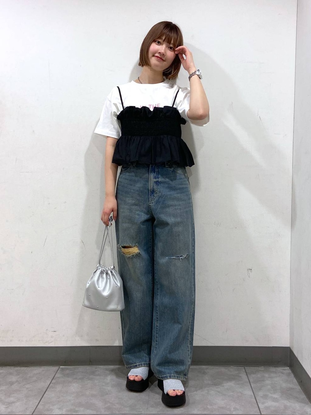 シルバー系のサンダル、シルバー系のショルダーバッグ、ブルー系のデニムパンツを着用したレディースの夏コーディネートの1枚目の写真