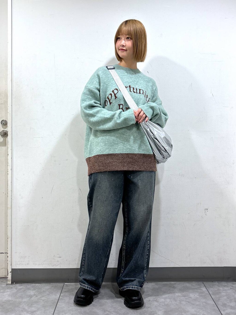 ブルー系のデニムパンツ、ブラック系のブーツ、グリーン系のニット/セーターを着用したレディースの秋コーディネートの1枚目の写真