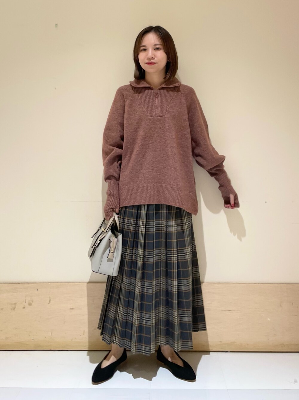 レッド系のニット/セーター、ブラック系のパンプス、グレー系のハンドバッグを着用したレディースの秋コーディネートの1枚目の写真