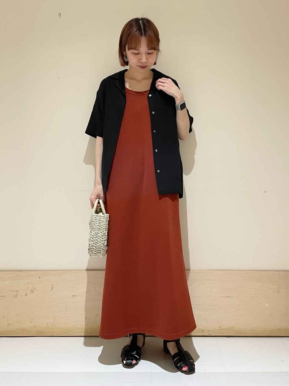 オレンジ系のワンピース、グレー系のかごバッグ、ブラック系のシャツ/ブラウスを着用したレディースの春コーディネートの1枚目の写真