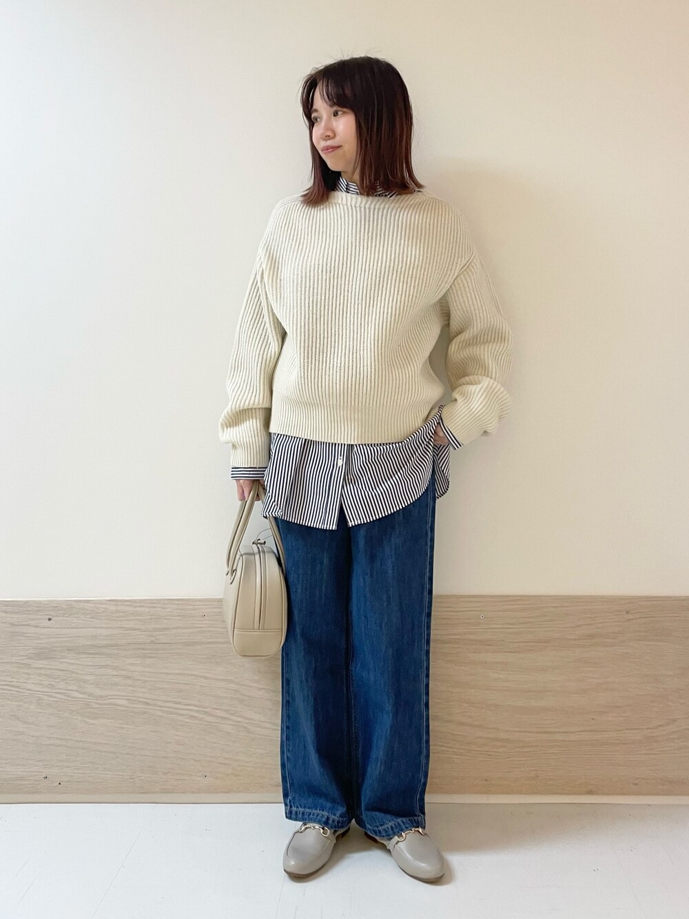 ホワイト系のニット/セーター、ブルー系のデニムパンツ、ベージュ系のボストンバッグを着用したレディースの冬コーディネートの1枚目の写真