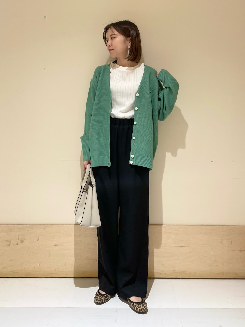 グリーン系のカーディガン/ボレロ、ホワイト系のTシャツ/カットソー、グレー系のトートバッグを着用したレディースの秋コーディネートの1枚目の写真