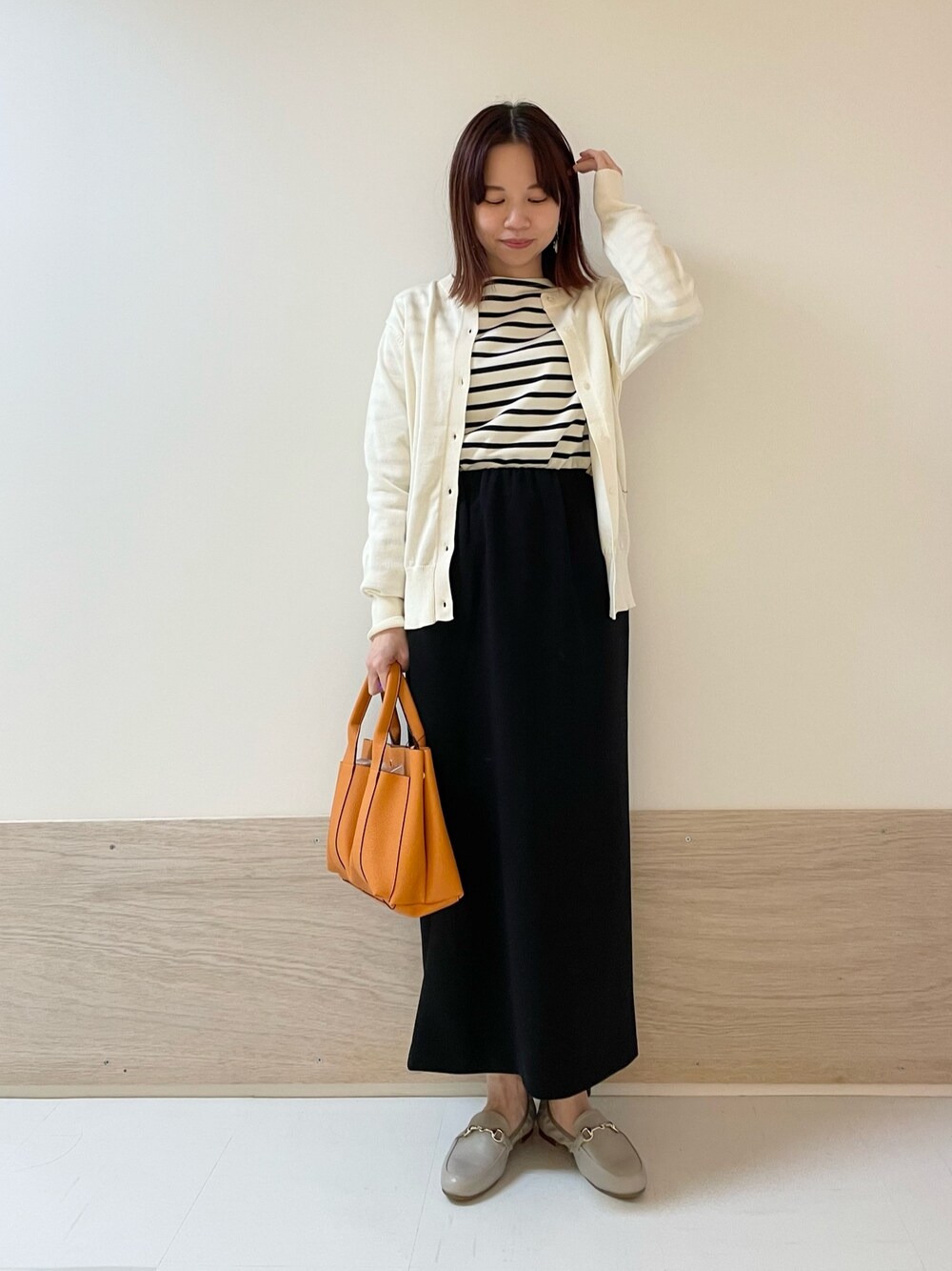 ブラック系のスカート、ホワイト系のカーディガン/ボレロ、ブルー系のTシャツ/カットソーを着用したレディースの春コーディネートの1枚目の写真