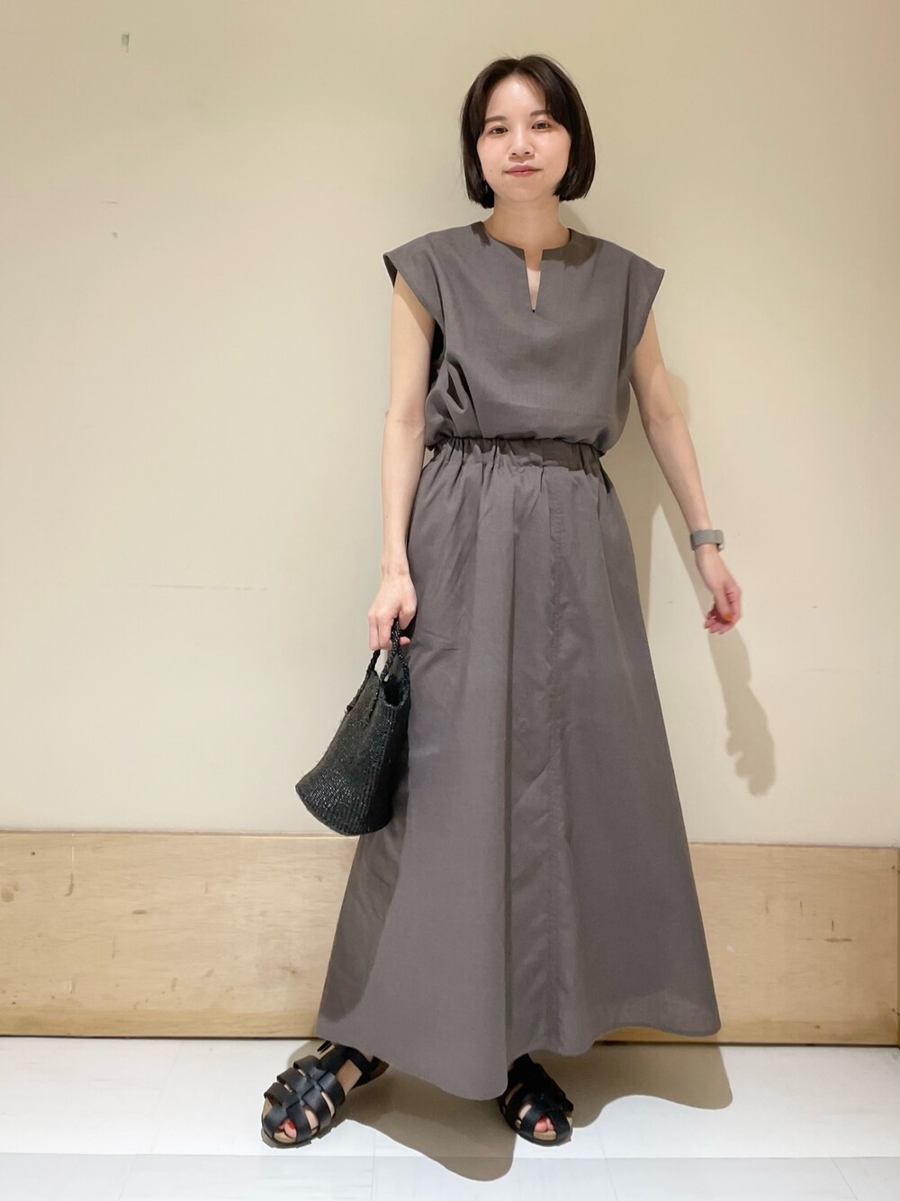 グレー系のシャツ/ブラウス、グレー系のスカート、ブラック系のサンダルを着用したレディースの夏コーディネートの1枚目の写真