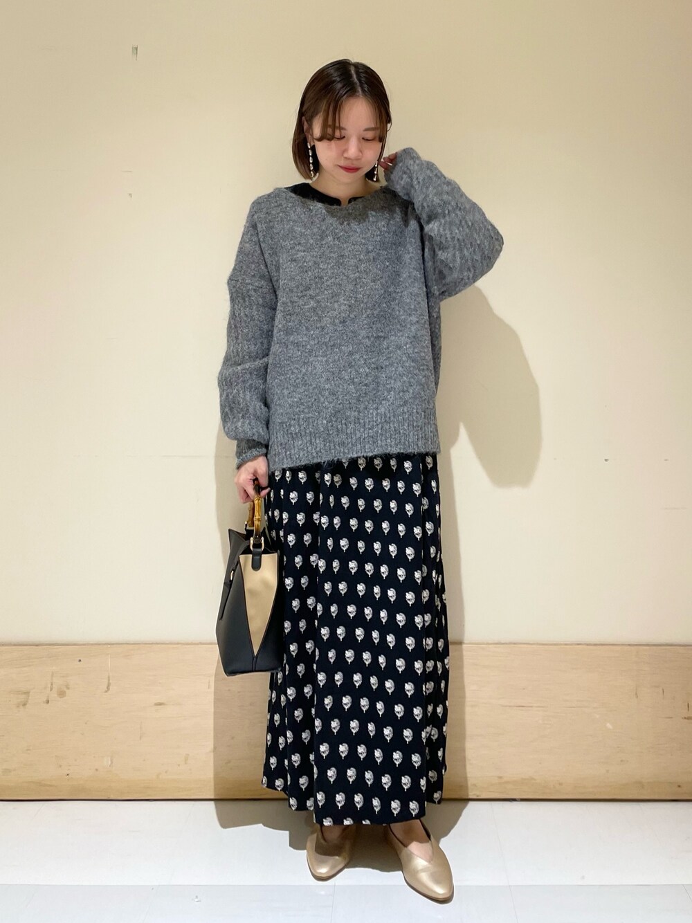 グレー系のニット/セーター、ブラック系のワンピース、ブラック系のハンドバッグを着用したレディースの秋コーディネートの1枚目の写真