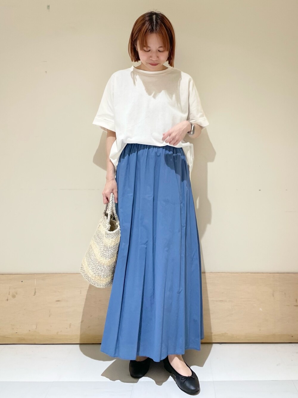 ホワイト系のTシャツ/カットソー、ブルー系のスカート、ホワイト系のハンドバッグを着用したレディースの夏コーディネートの1枚目の写真