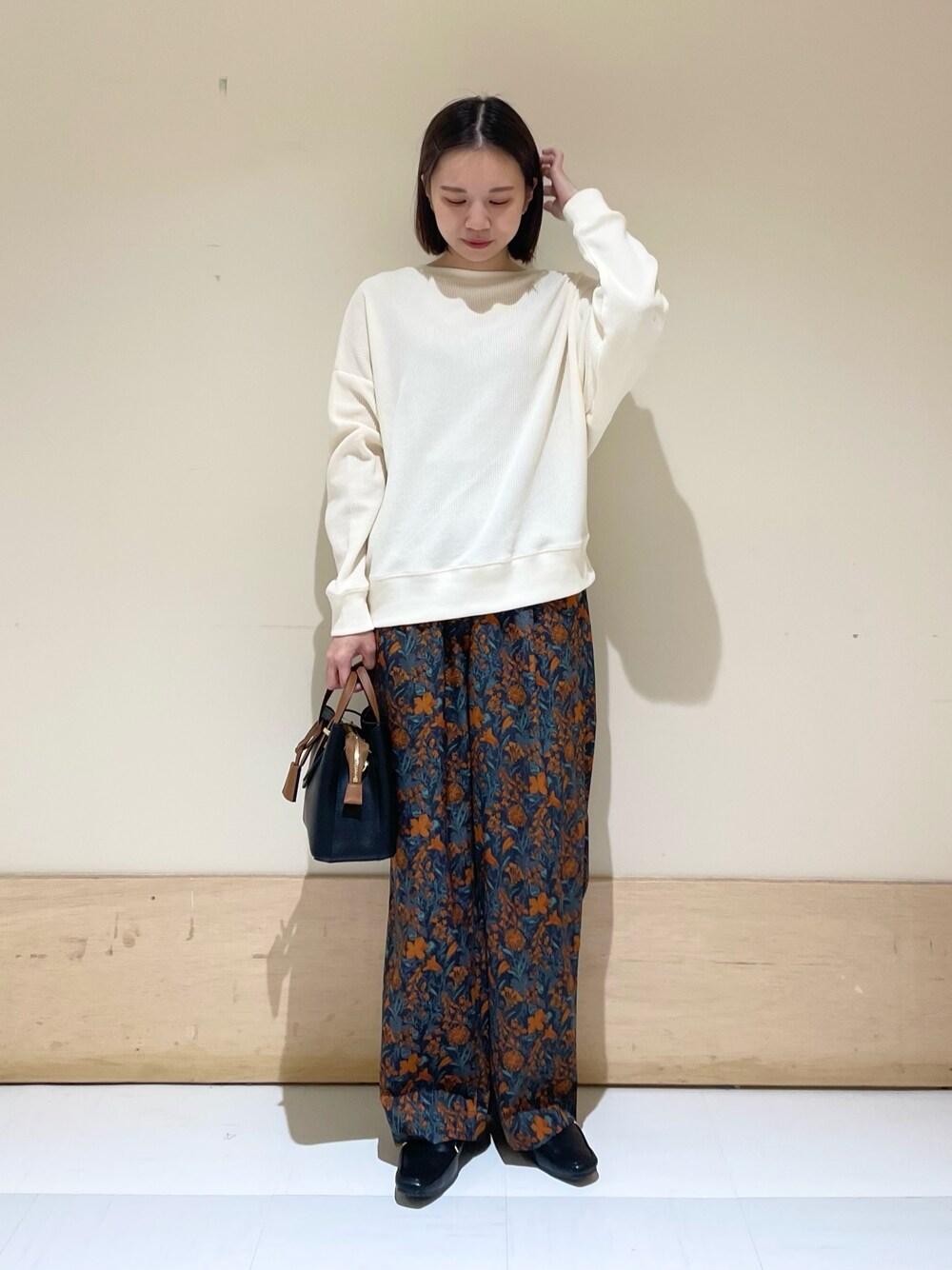 オレンジ系のその他パンツ、ブラック系のハンドバッグ、ブラック系のローファーを着用したレディースの秋コーディネートの1枚目の写真