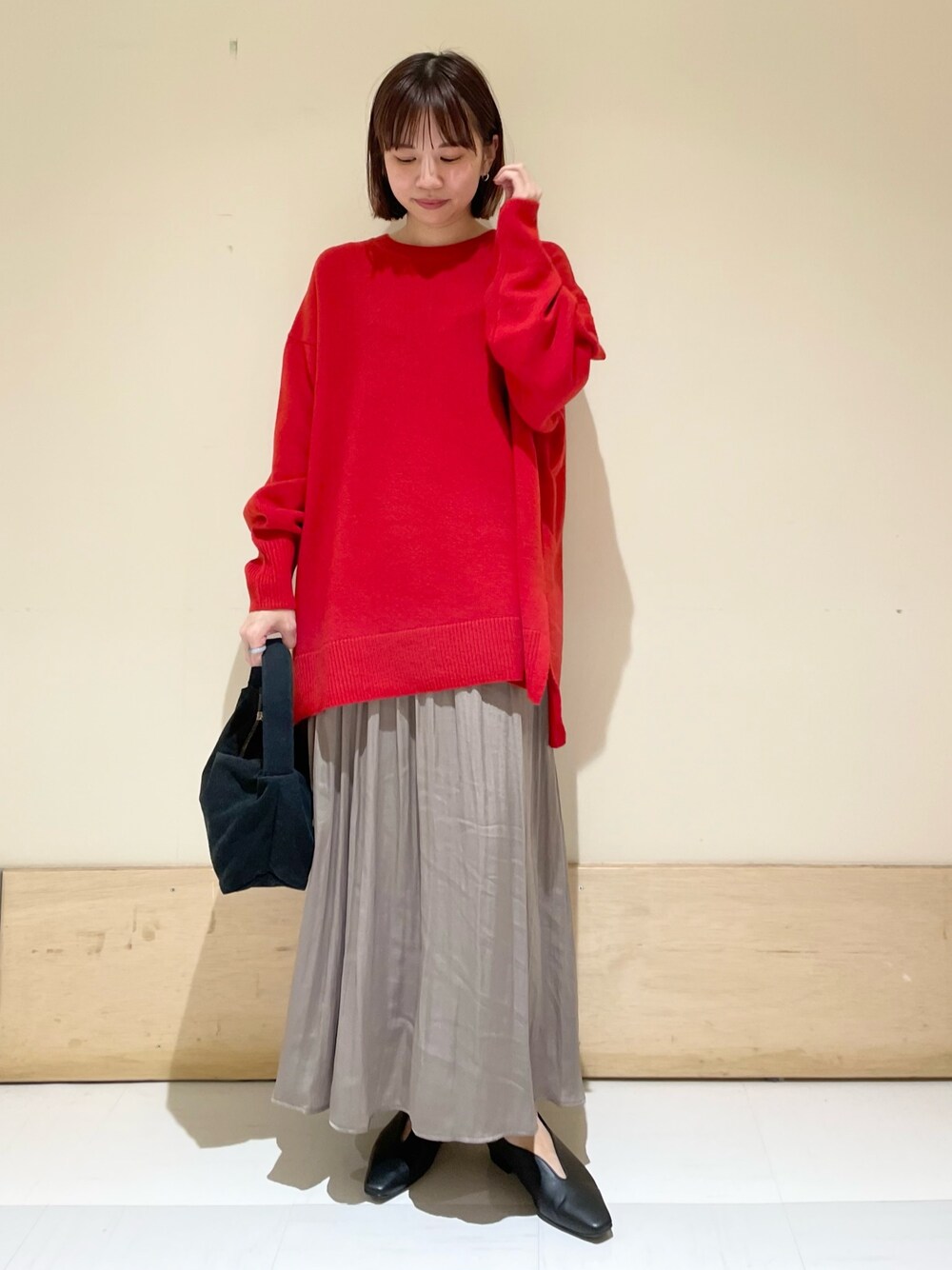 ブラック系のハンドバッグ、グレー系のスカート、ブラック系のパンプスを着用したレディースの秋コーディネートの1枚目の写真