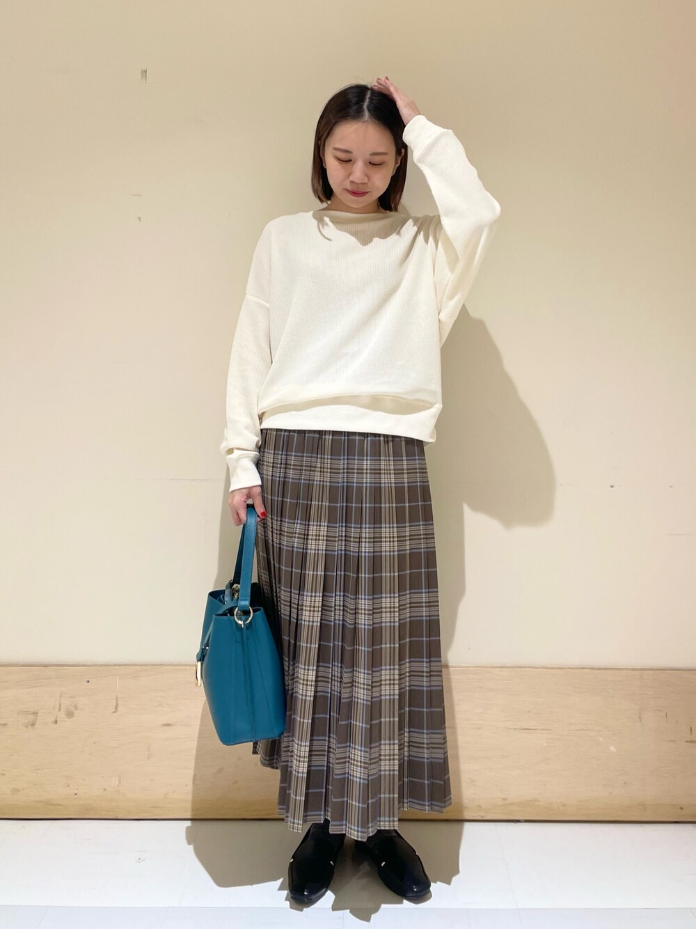 ブルー系のハンドバッグ、ブラック系のローファー、ベージュ系のTシャツ/カットソーを着用したレディースの秋コーディネートの1枚目の写真