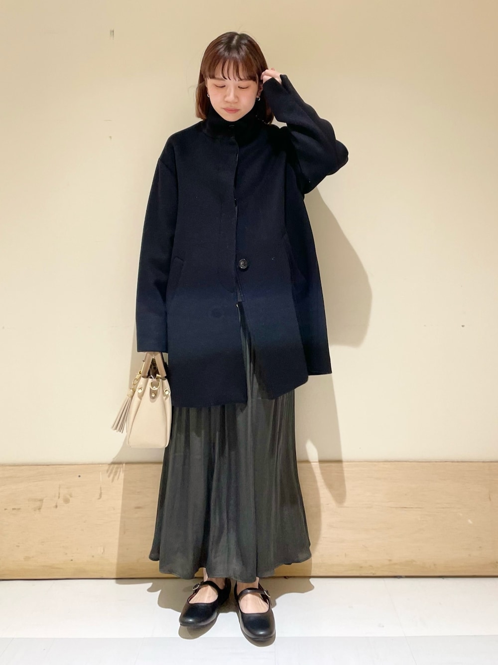 グリーン系のスカート、グレー系のニット/セーター、ブラック系のその他アウターを着用したレディースの冬コーディネートの1枚目の写真