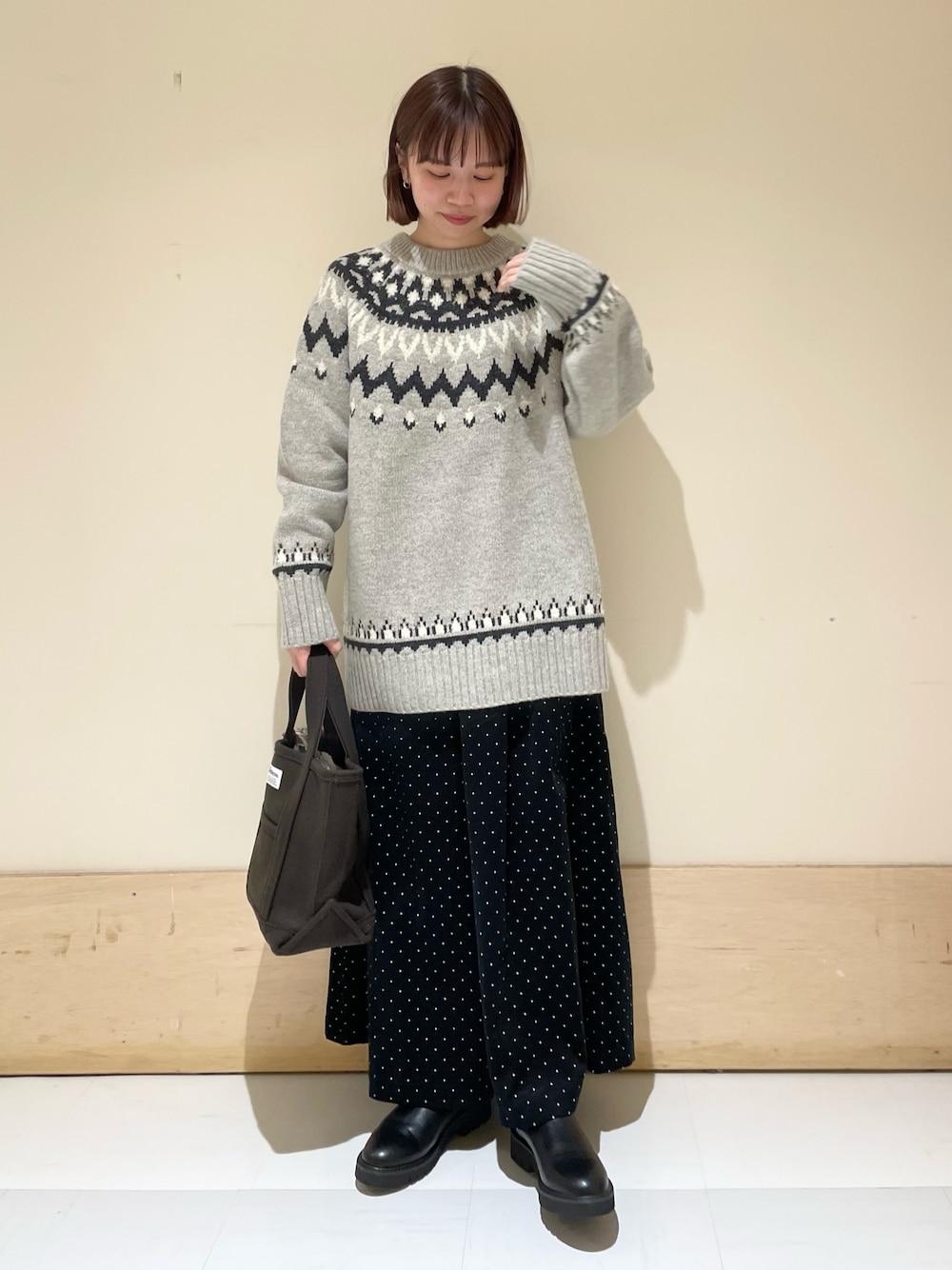 グレー系のニット/セーター、ブラック系のブーツ、ブラウン系のトートバッグを着用したレディースの秋コーディネートの1枚目の写真