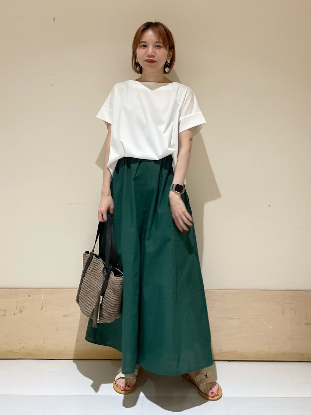 ホワイト系のTシャツ/カットソー、グレー系のトートバッグ、グリーン系のスカートを着用したレディースの夏コーディネートの1枚目の写真