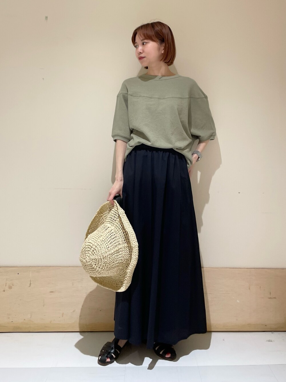 ブルー系のスカート、ブラック系のサンダル、グリーン系のTシャツ/カットソーを着用したレディースの春コーディネートの1枚目の写真