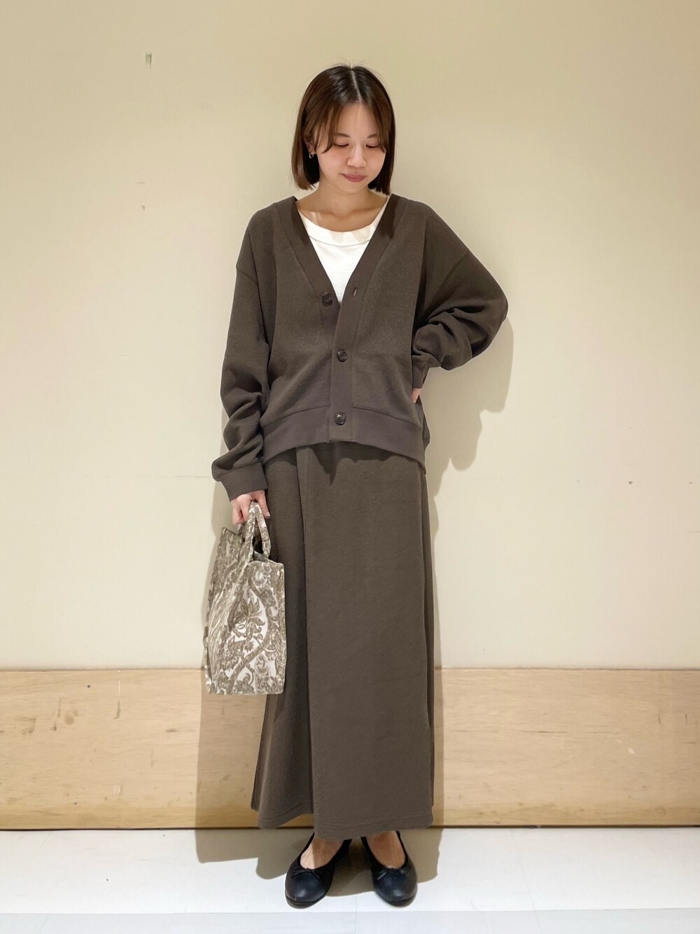 ベージュ系のトートバッグ、ホワイト系のタンクトップ、グレー系のカーディガン/ボレロを着用したレディースの秋コーディネートの1枚目の写真