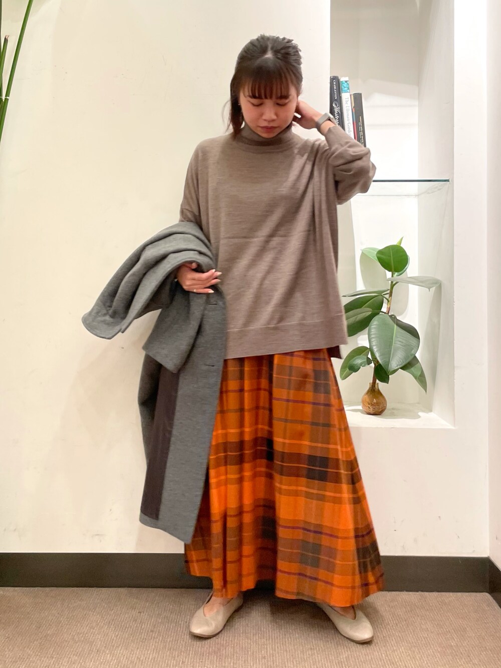 グレー系のニット/セーター、オレンジ系のスカート、グレー系のチェスターコートを着用したレディースの秋コーディネートの1枚目の写真