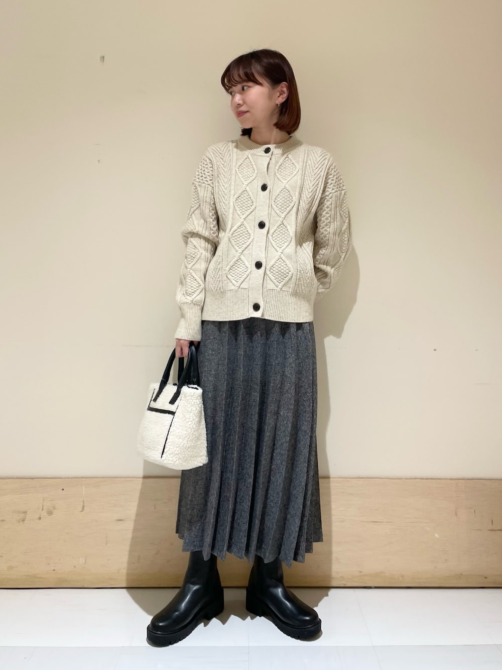 ホワイト系のカーディガン/ボレロ、ブルー系のスカート、ホワイト系のショルダーバッグを着用したレディースの冬コーディネートの1枚目の写真