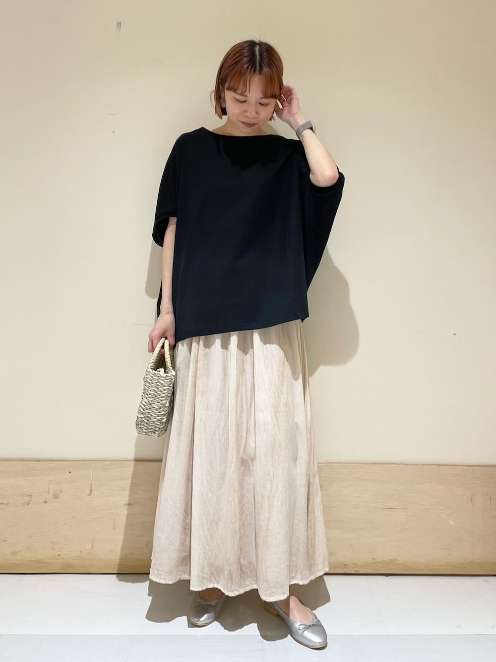 グレー系のかごバッグ、シルバー系のバレエシューズ、ブラック系のTシャツ/カットソーを着用したレディースの春コーディネートの1枚目の写真