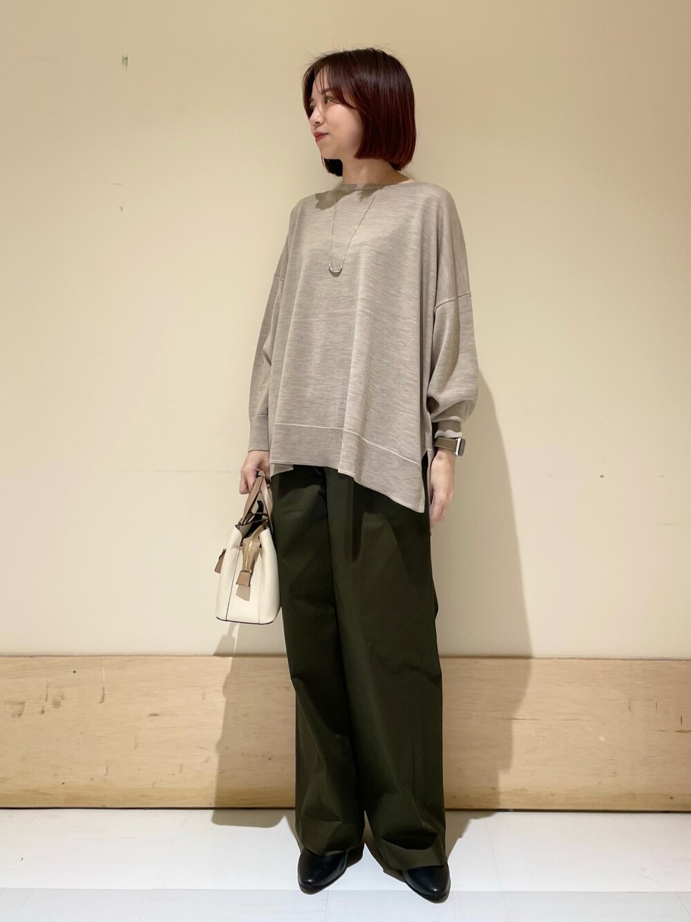 ブラック系のパンプス、ベージュ系のニット/セーター、ホワイト系のハンドバッグを着用したレディースの秋コーディネートの1枚目の写真