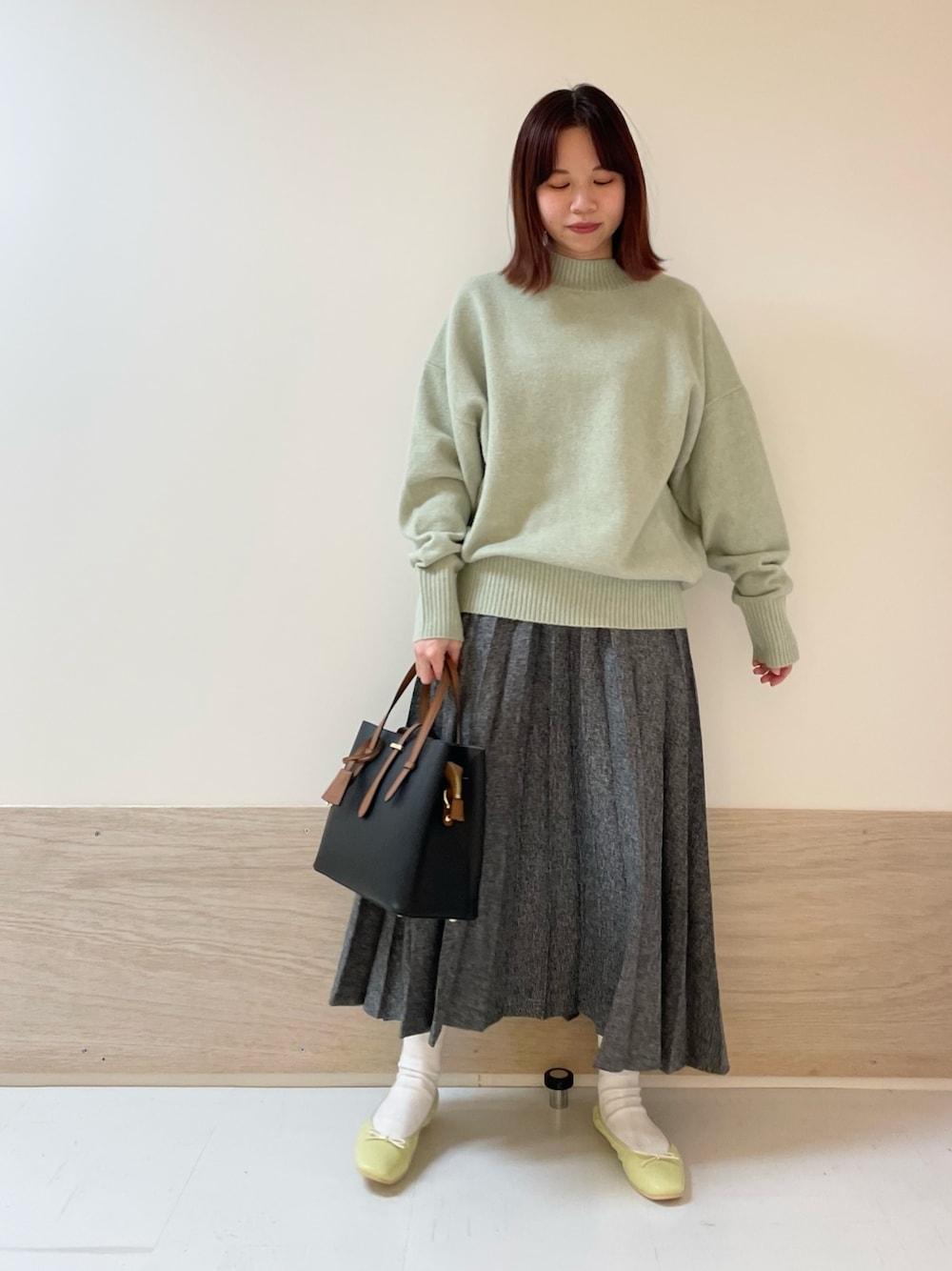 グリーン系のニット/セーター、イエロー系のバレエシューズ、ブルー系のスカートを着用したレディースの冬コーディネートの1枚目の写真