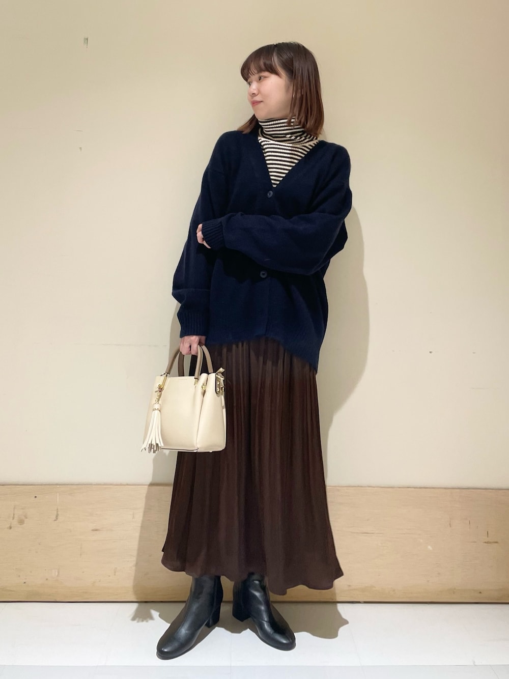 ブルー系のカーディガン/ボレロ、ホワイト系のニット/セーター、ブラウン系のスカートを着用したレディースの冬コーディネートの1枚目の写真