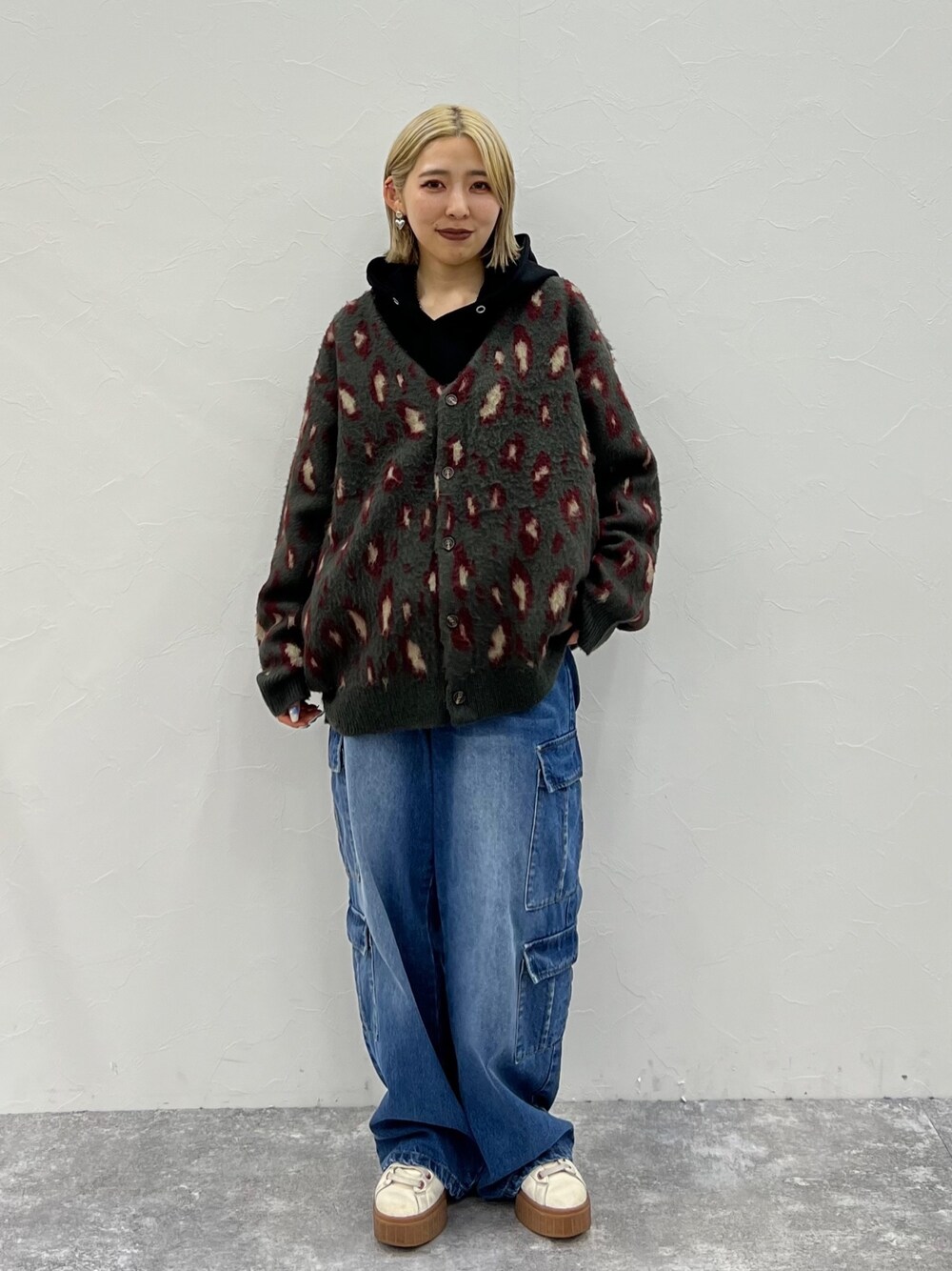 レッド系のカーディガン/ボレロ、ブラック系のパーカー、ブルー系のデニムパンツを着用したレディースの秋コーディネートの1枚目の写真