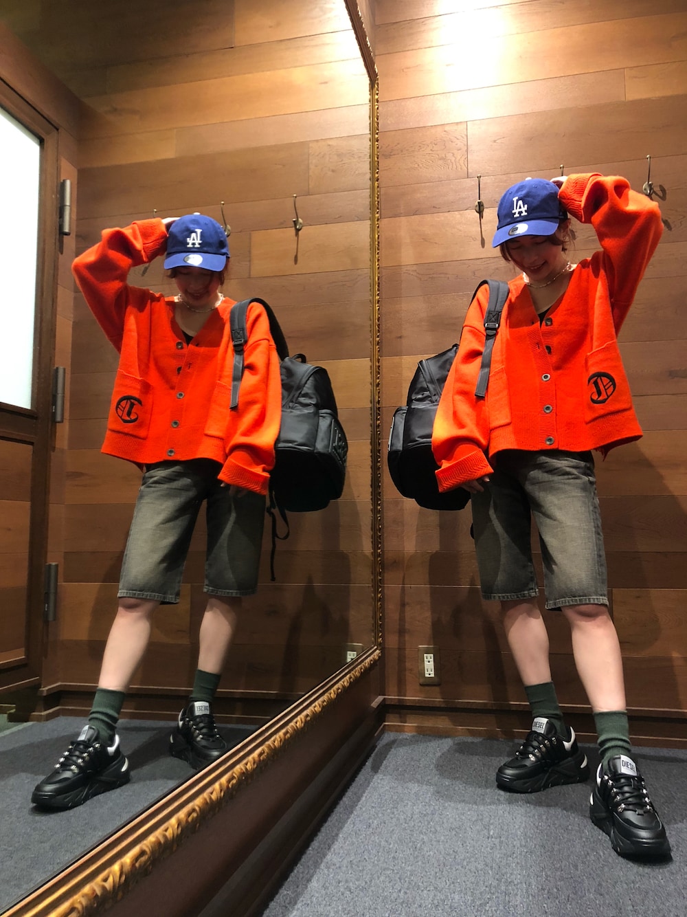 ブラック系のスニーカー、レッド系のカーディガン/ボレロ、ブラック系のバックパック/リュックを着用したレディースの秋コーディネートの1枚目の写真