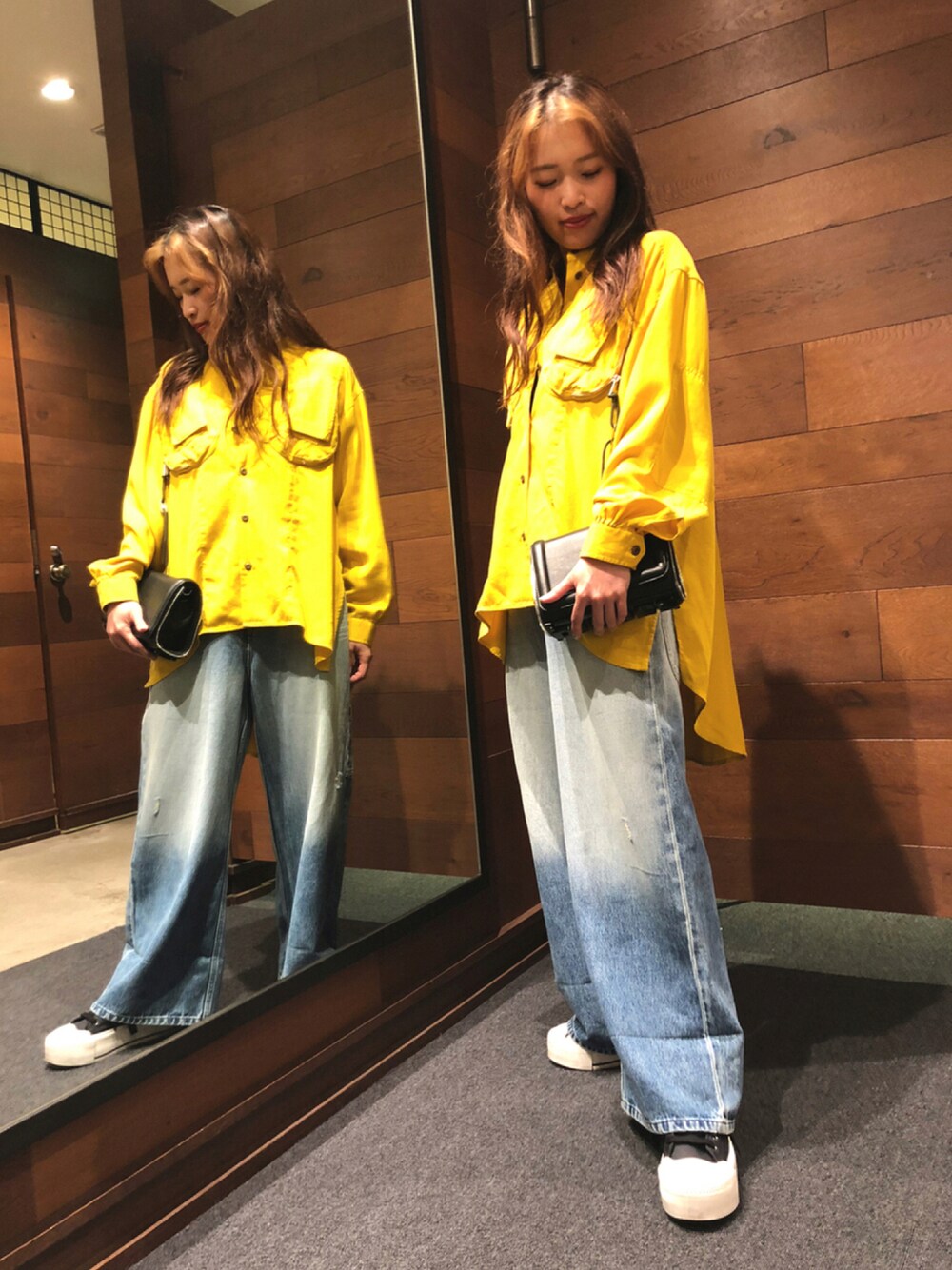 ブラック系のスニーカー、ブルー系のデニムパンツ、ブラック系のショルダーバッグを着用したレディースの夏コーディネートの1枚目の写真