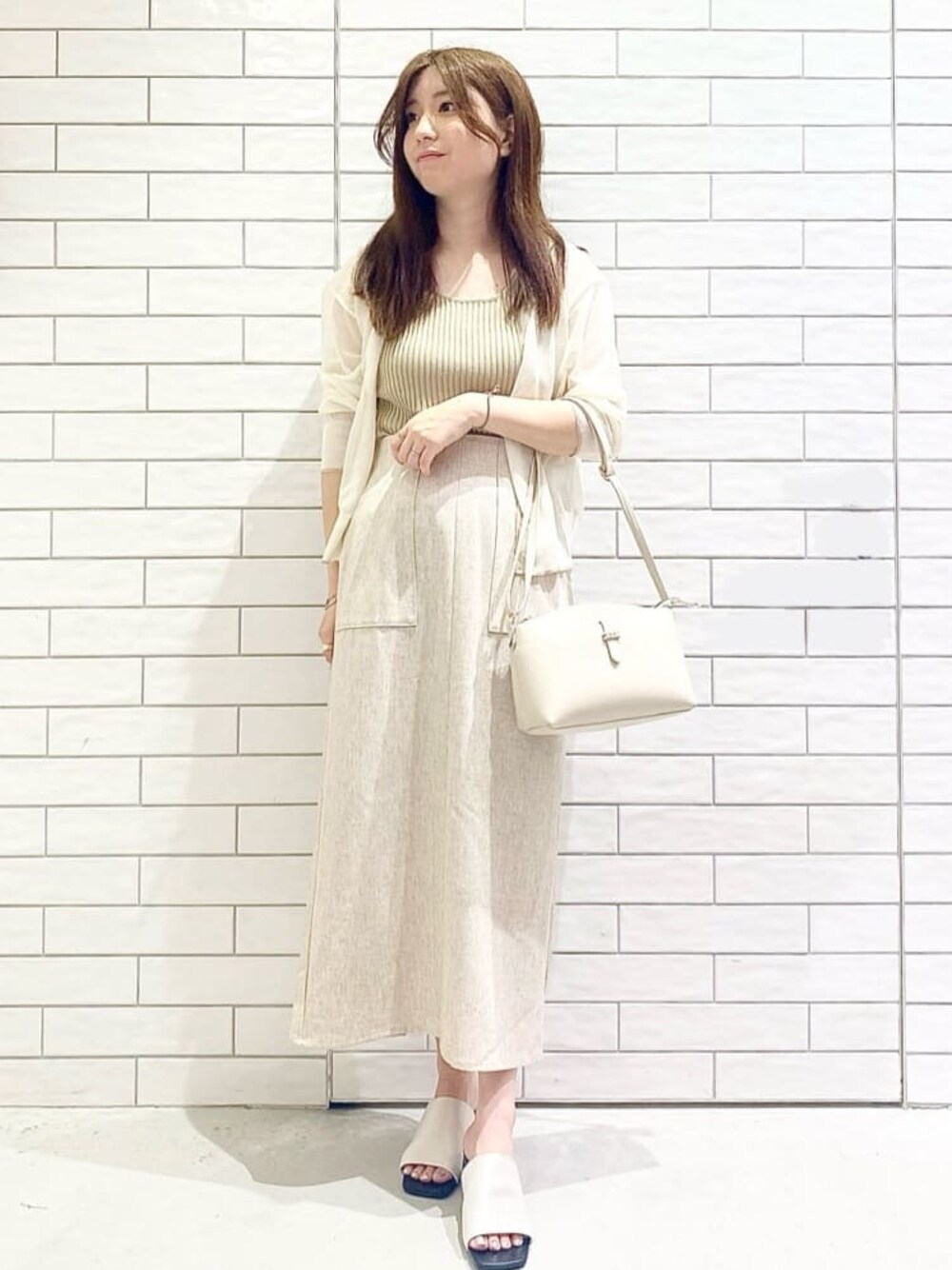 ホワイト系のカーディガン/ボレロ、ベージュ系のニット/セーター、ホワイト系のサンダルを着用したレディースの夏コーディネートの1枚目の写真
