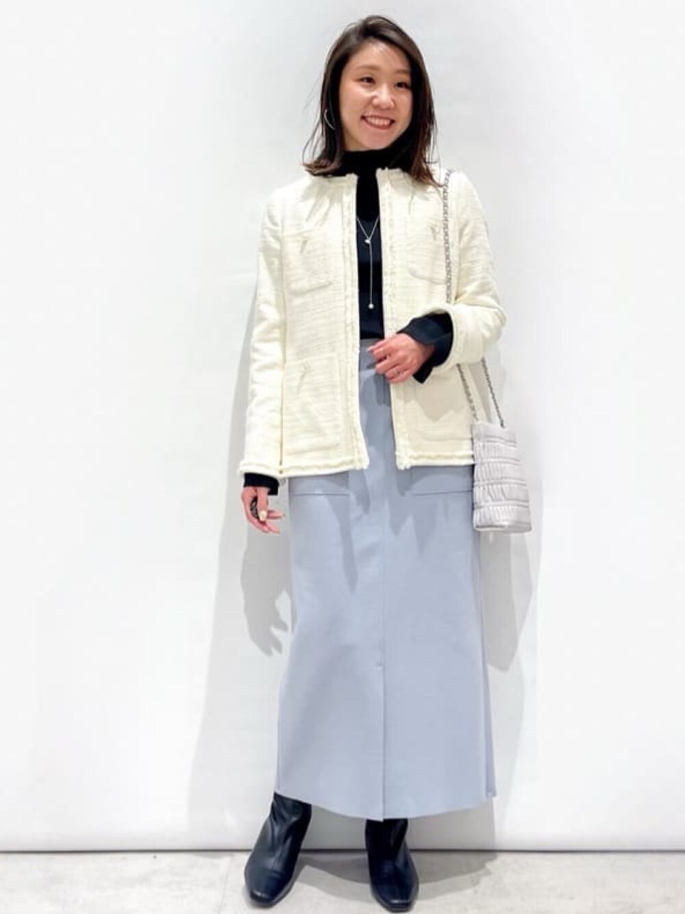 ブラック系のニット/セーター、ホワイト系のノーカラージャケット、グレー系のショルダーバッグを着用したレディースの冬コーディネートの1枚目の写真