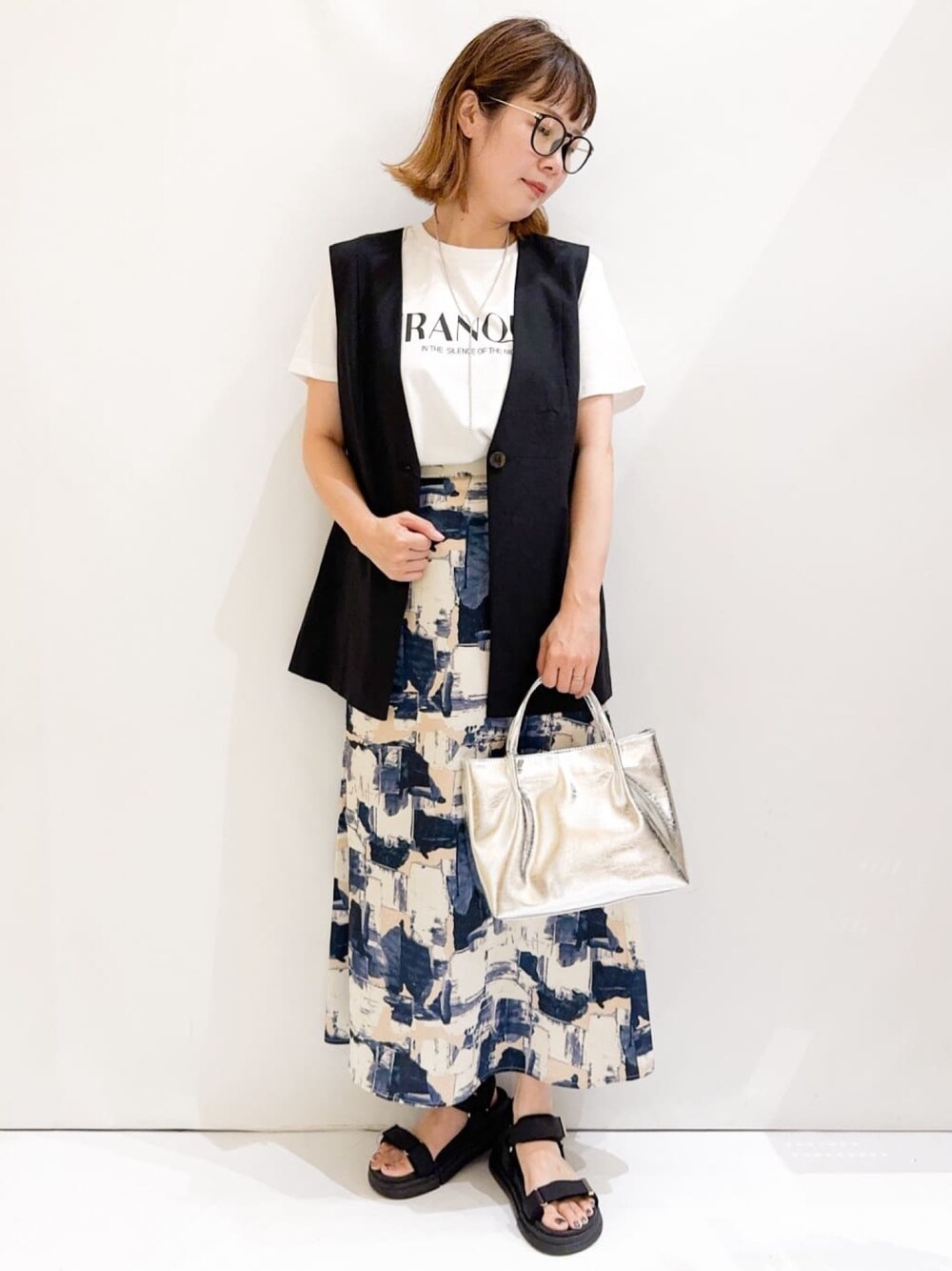 ホワイト系のTシャツ/カットソー、ブラック系のベスト、シルバー系のトートバッグを着用したレディースの夏コーディネートの1枚目の写真