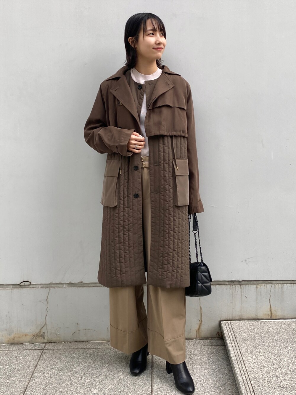グリーン系のトレンチコート、ベージュ系のその他パンツ、ブラック系のショルダーバッグを着用したレディースの秋コーディネートの1枚目の写真
