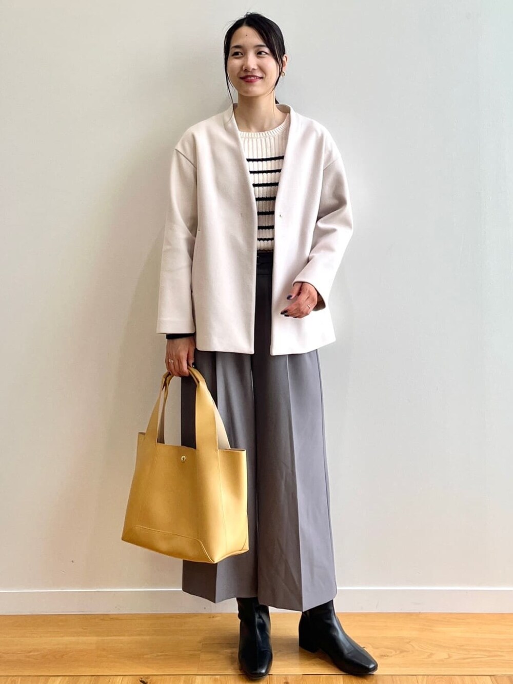 ホワイト系のノーカラーコート、ホワイト系のニット/セーター、グレー系のその他パンツを着用したレディースの秋コーディネートの1枚目の写真