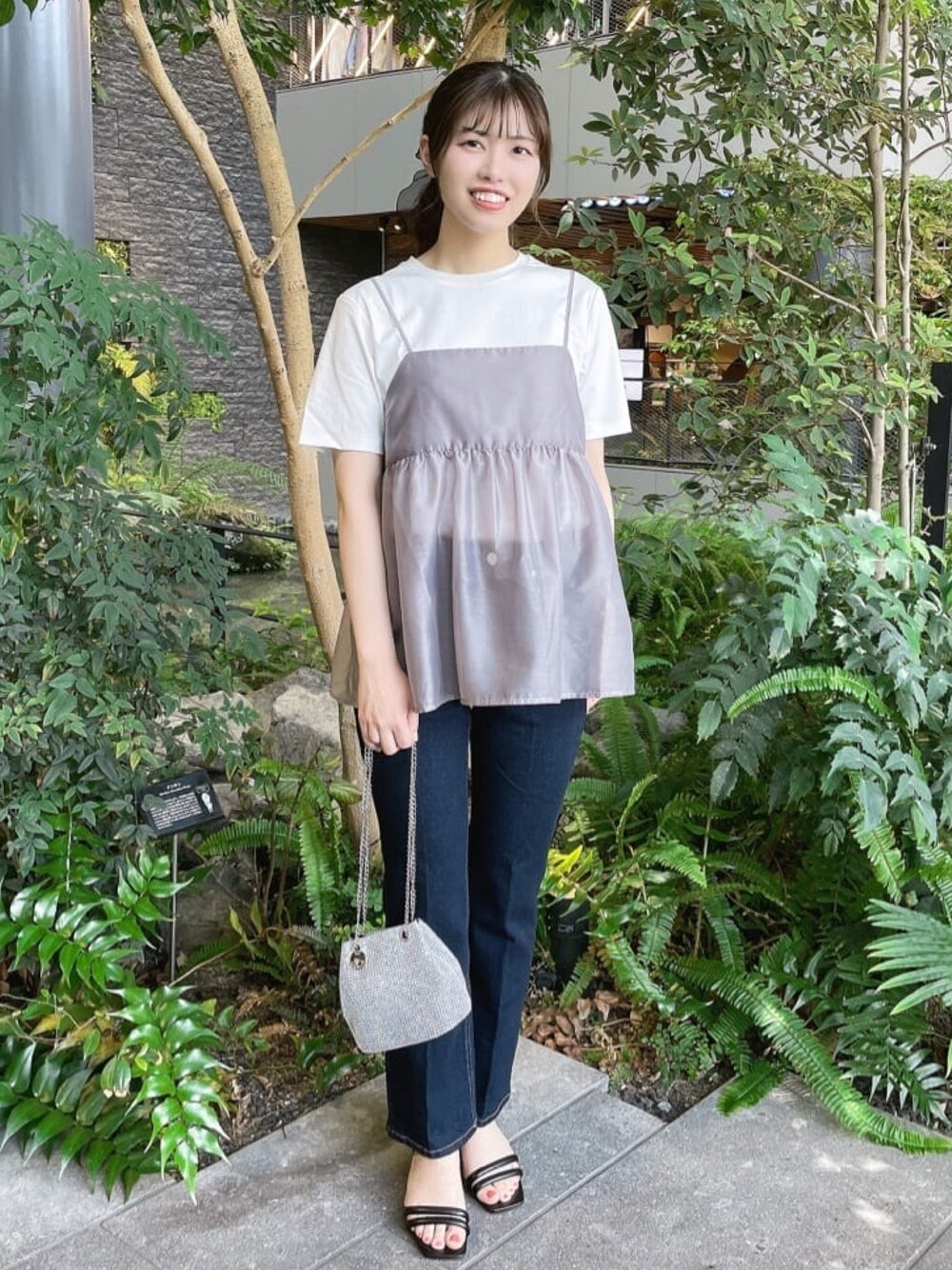 グレー系のタンクトップ、ホワイト系のTシャツ/カットソー、ブルー系のデニムパンツを着用したレディースの春コーディネートの1枚目の写真
