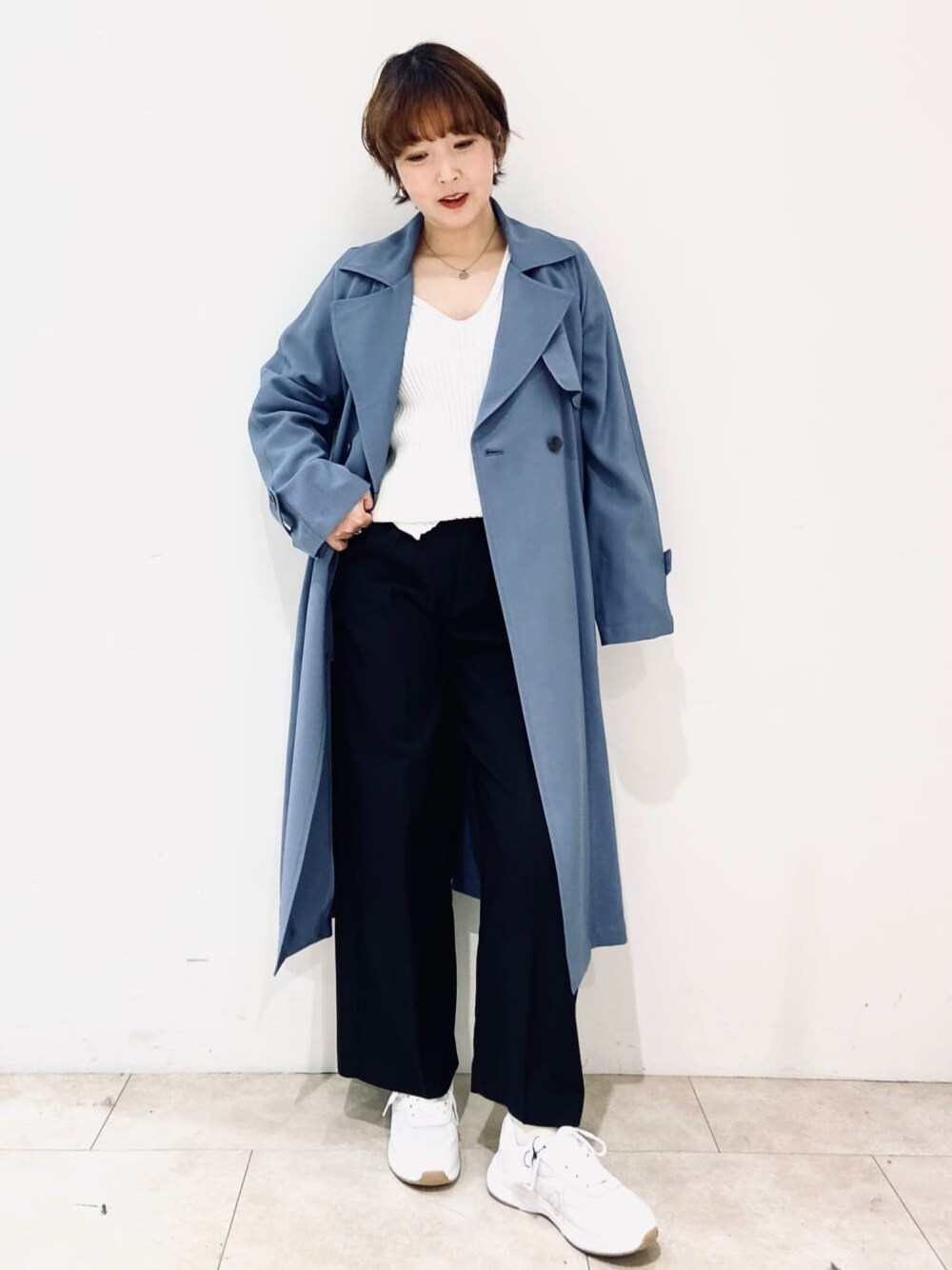 ブルー系のトレンチコート、ホワイト系のニット/セーター、ブルー系のその他パンツを着用したレディースの冬コーディネートの1枚目の写真
